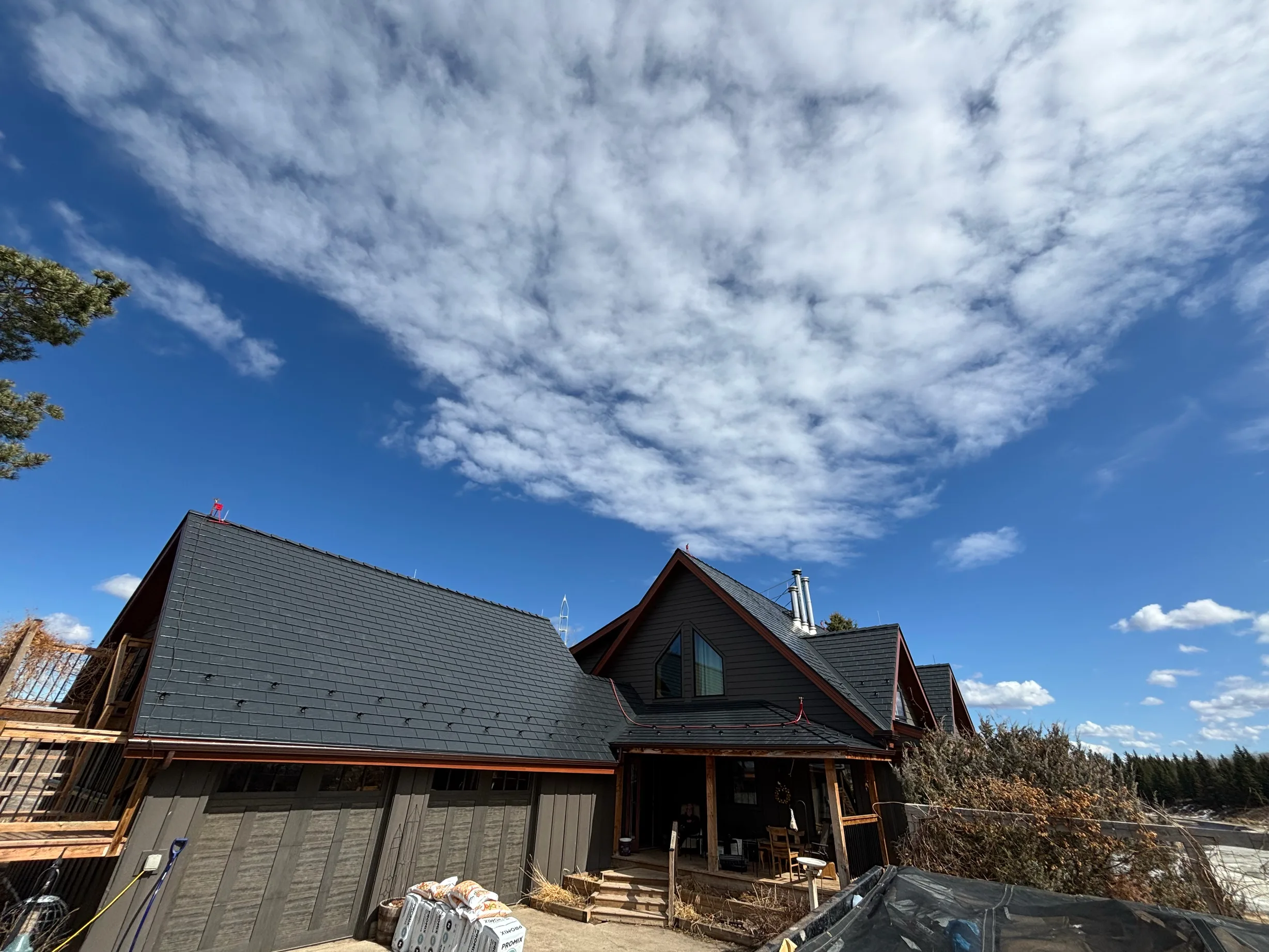 Black Interlock Slate aluminum roof on a brown, one-storey chalet with a gabled roof in a forested, Wildwood, Alberta
