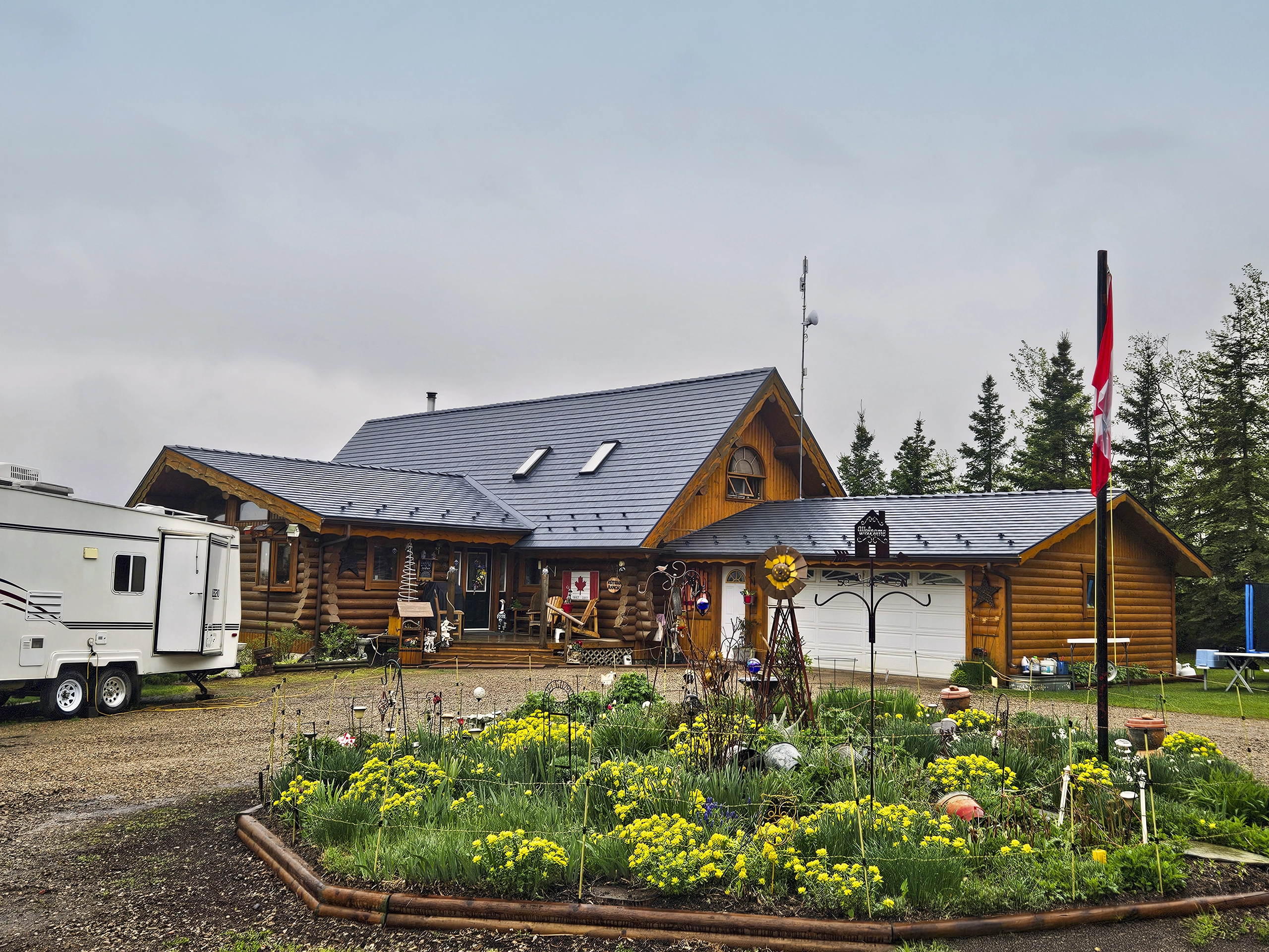 Log cabin-style home in rural Alberta with Interlock deep charcoal cedar shingle metal roof featuring skylights, dormers, and complex multi-plane roofline.
