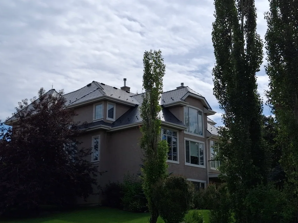 Deep Charcoal Interlock Slate aluminum roof on a beige modern single-family home with lush greenery in the, Calgary, Alberta