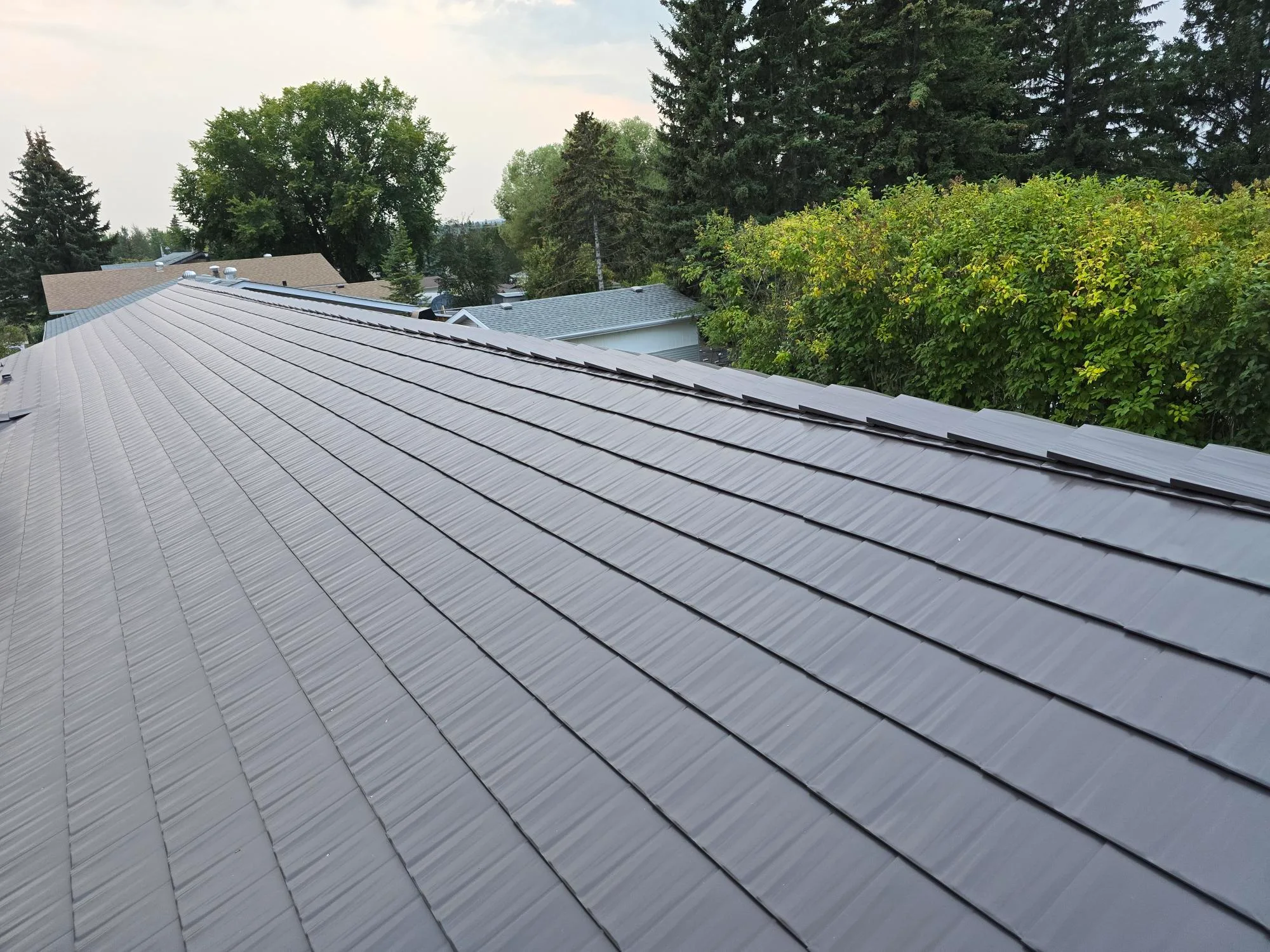Tudor Brown Interlock Cedar Shingle aluminum roof on a Tudor brown metal roof on a single-family home among tall, Rocky Mountain House, Alberta