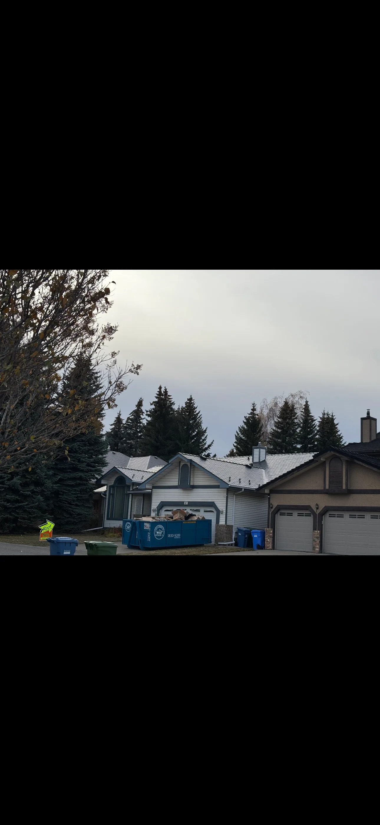 Musket Grey Interlock Slate aluminum roof being installed on a two-storey house with a metal roof under construction in, Calgary, Alberta