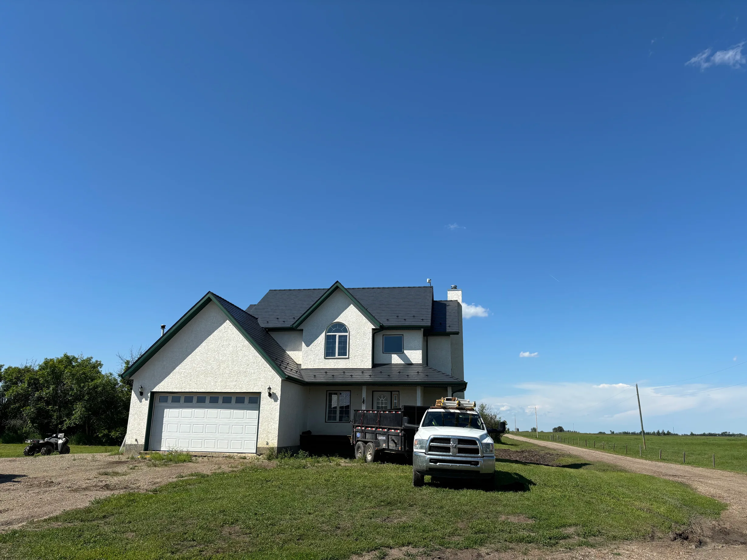 Deep Charcoal Interlock Slate aluminum roof on a beige two-storey home with a metal roof on a rural acreage, Fairview, Alberta