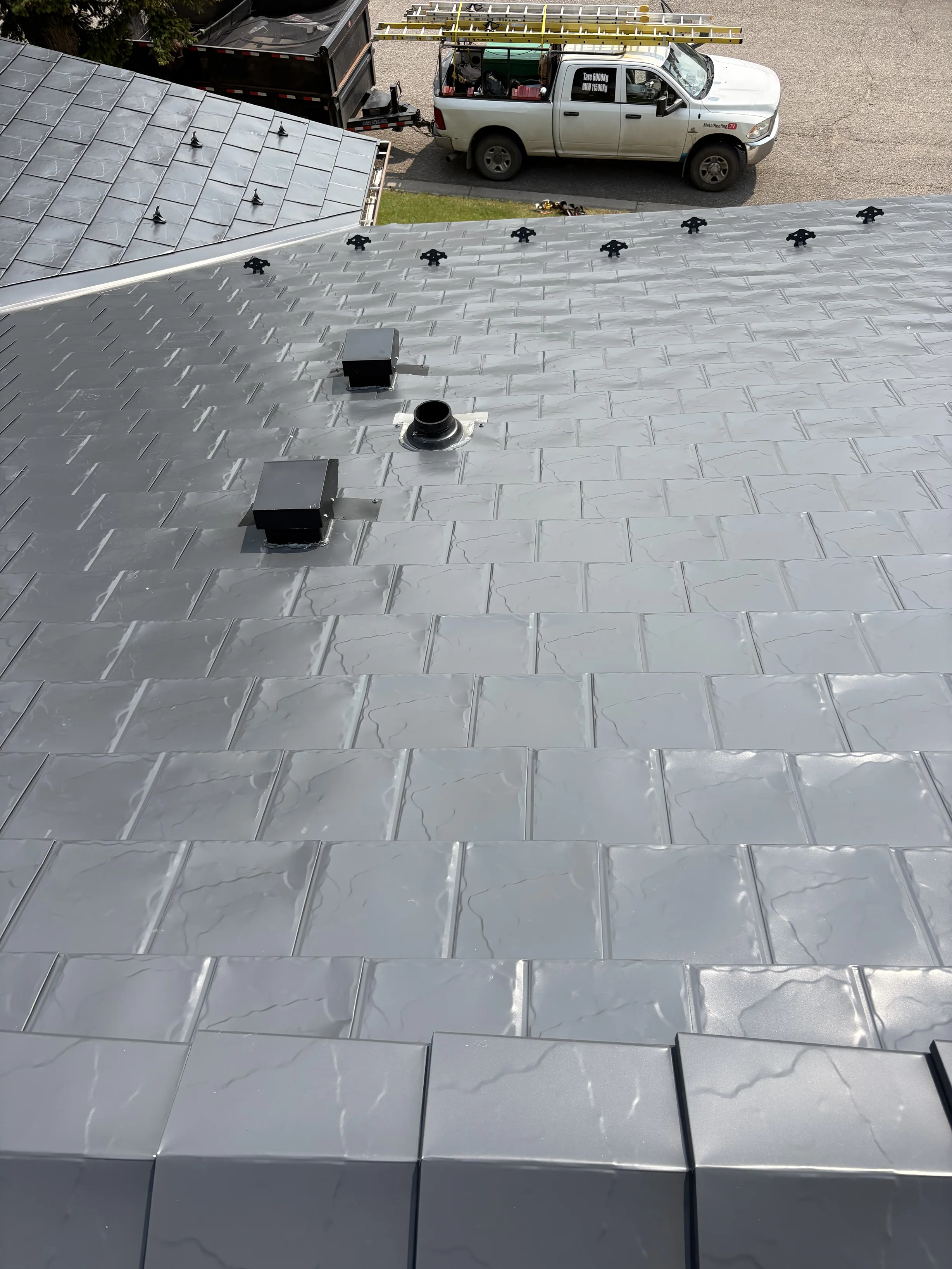 Deep Charcoal Interlock Slate aluminum roof on a modern home with a metal roof among rural fields, Coleman, Alberta