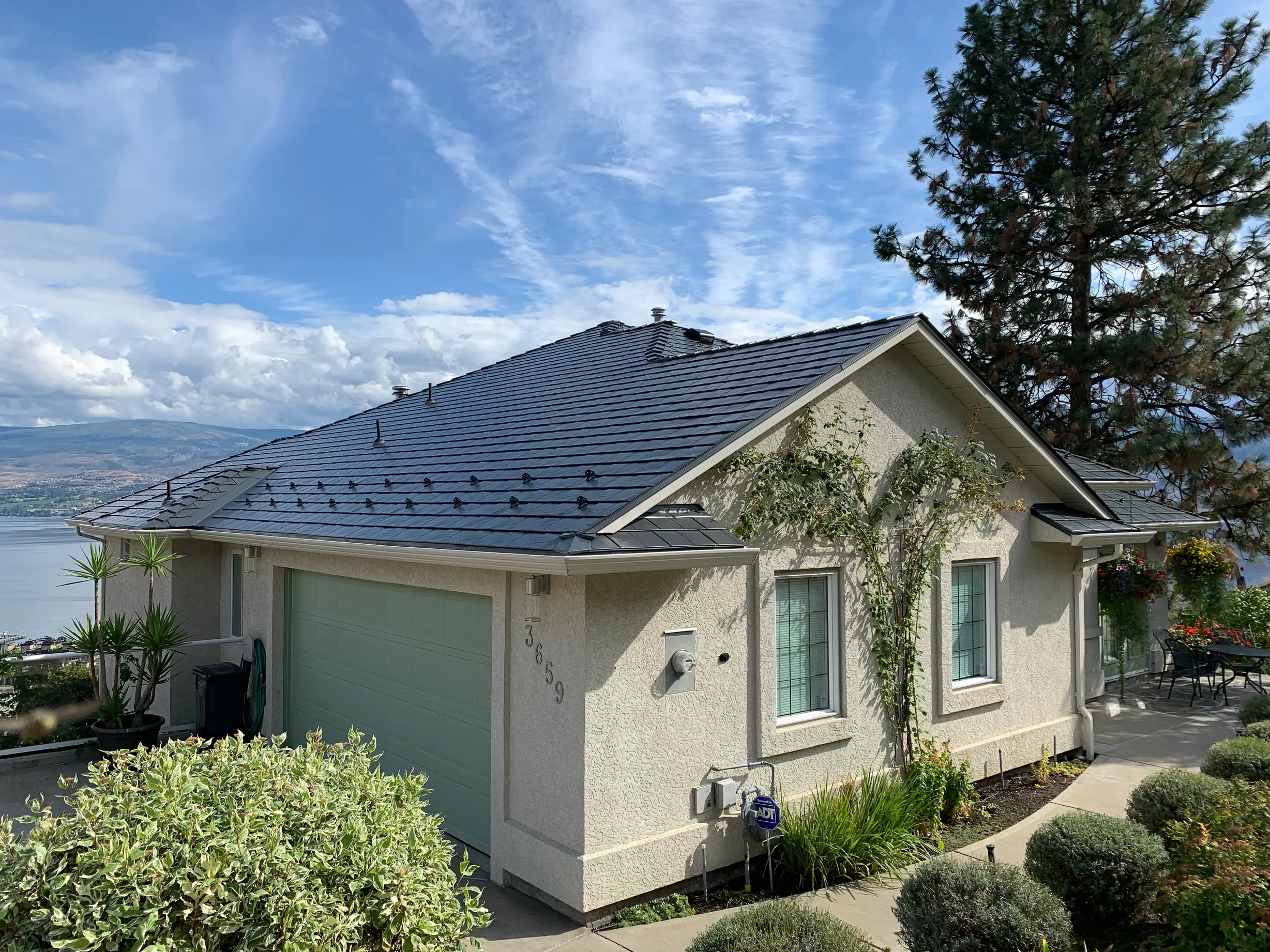 Deep Charcoal Interlock Slate aluminum roof on a white modern home with a metal roof in the mountains, West Kelowna, British Columbia