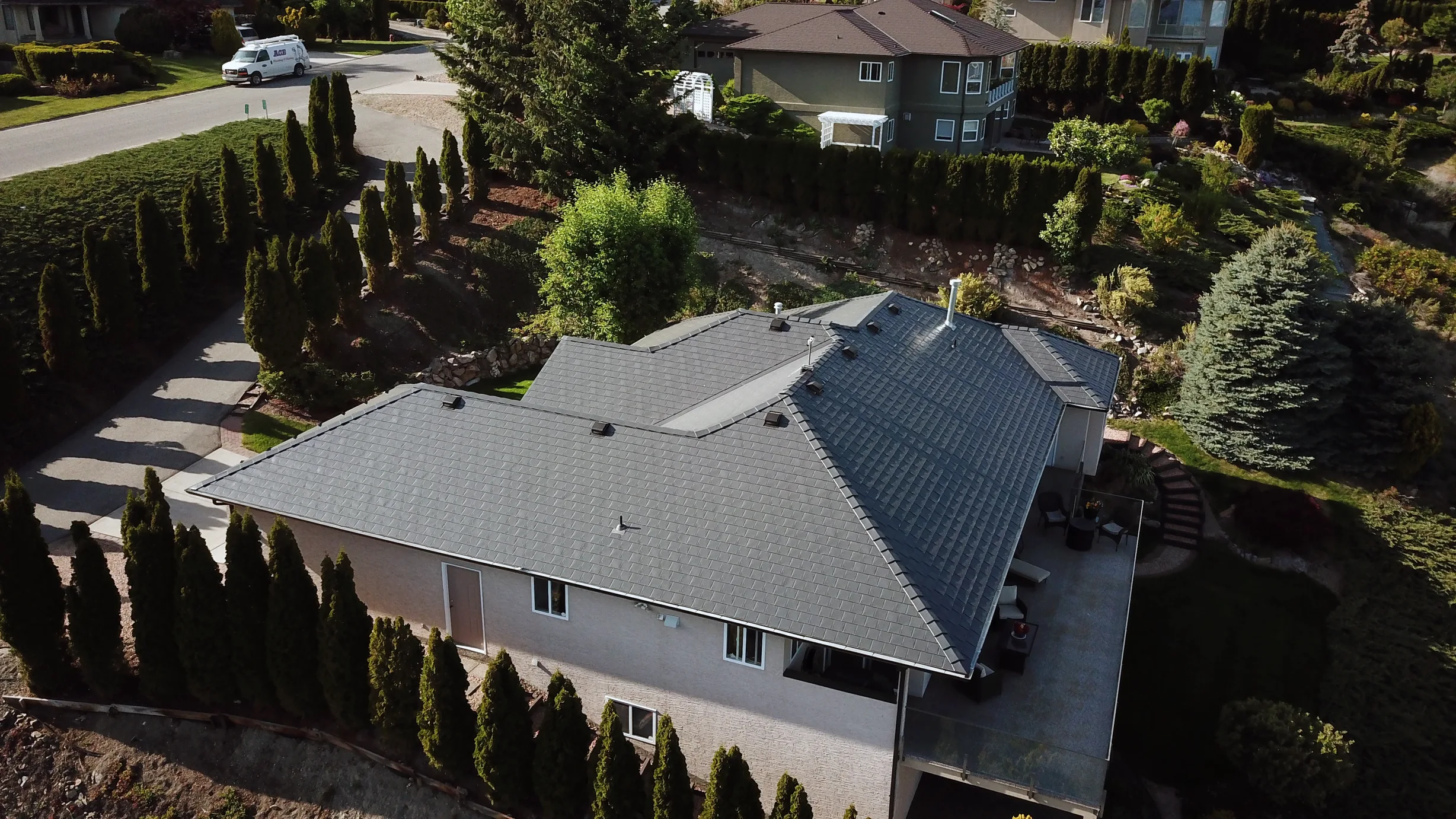 Deep Charcoal Interlock Slate aluminum roof on a beige single-family home with dormers in a mountain, West Kelowna, British Columbia
