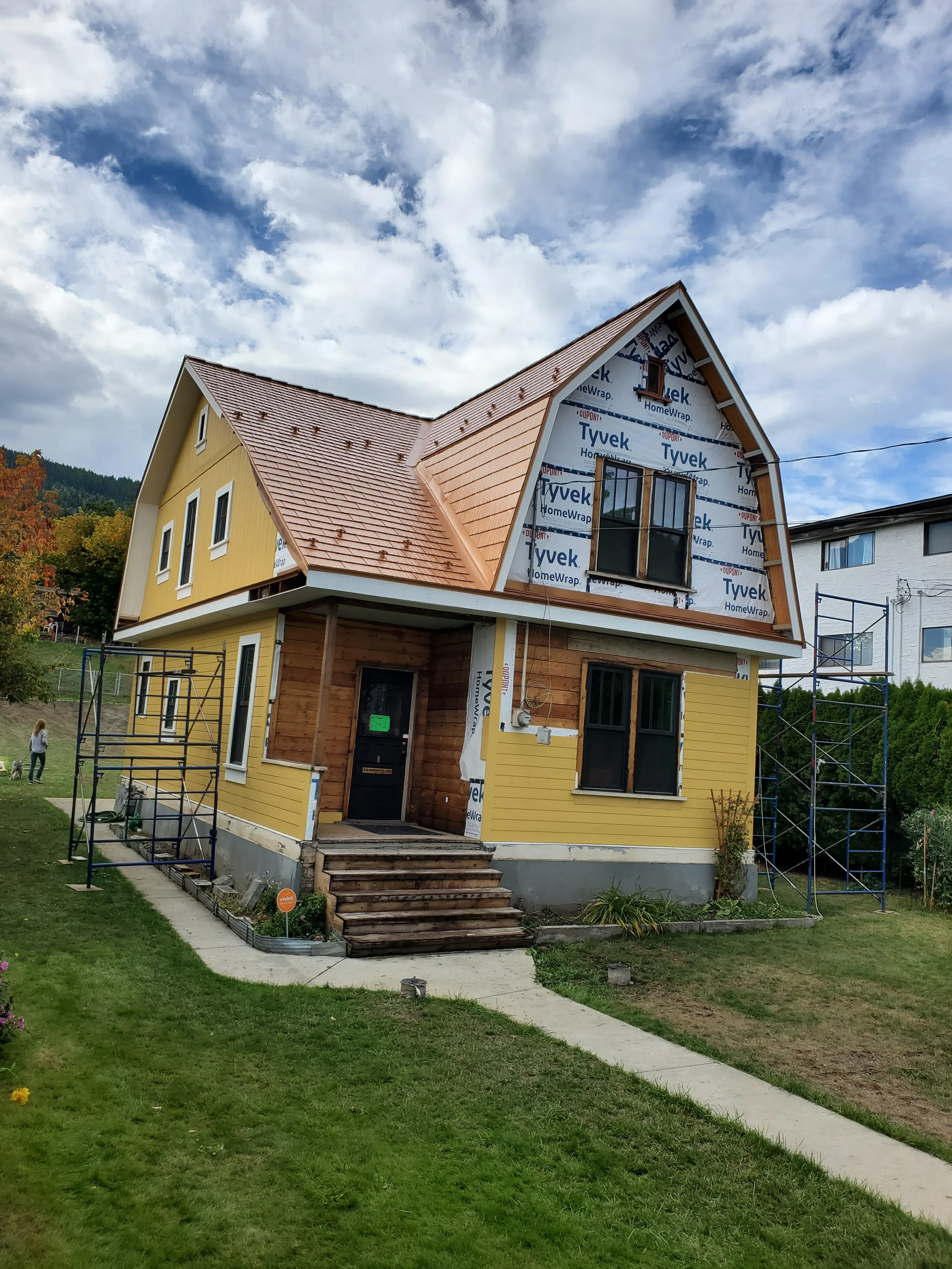 Copper Penny Interlock Cedar Shingle aluminum roof on a yellow home with dormers among tall pines, Lumby, British Columbia