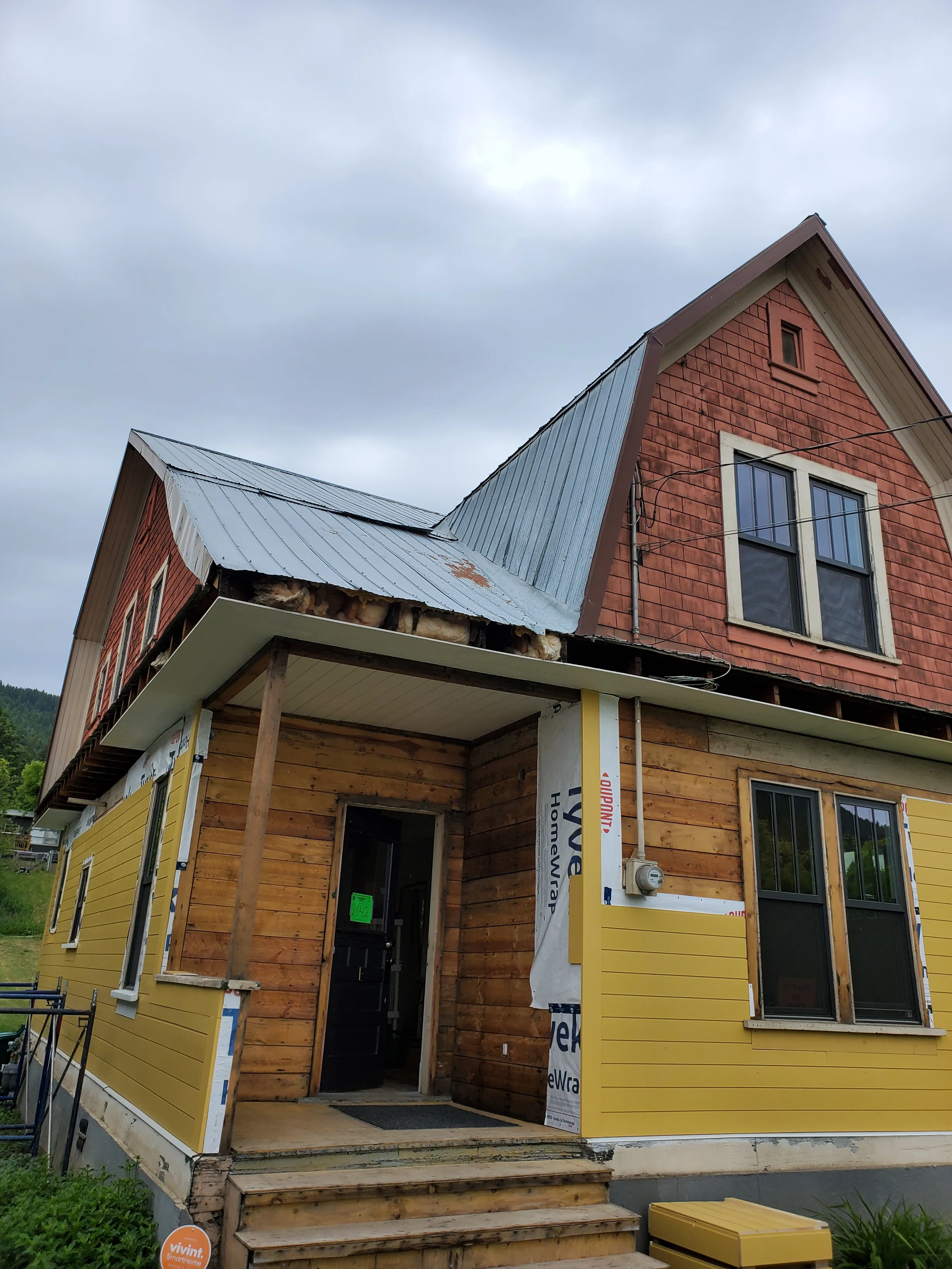 Copper Penny Interlock Cedar Shingle aluminum roof on a yellow cottage with dormers among tall pine trees, Lumby, British Columbia