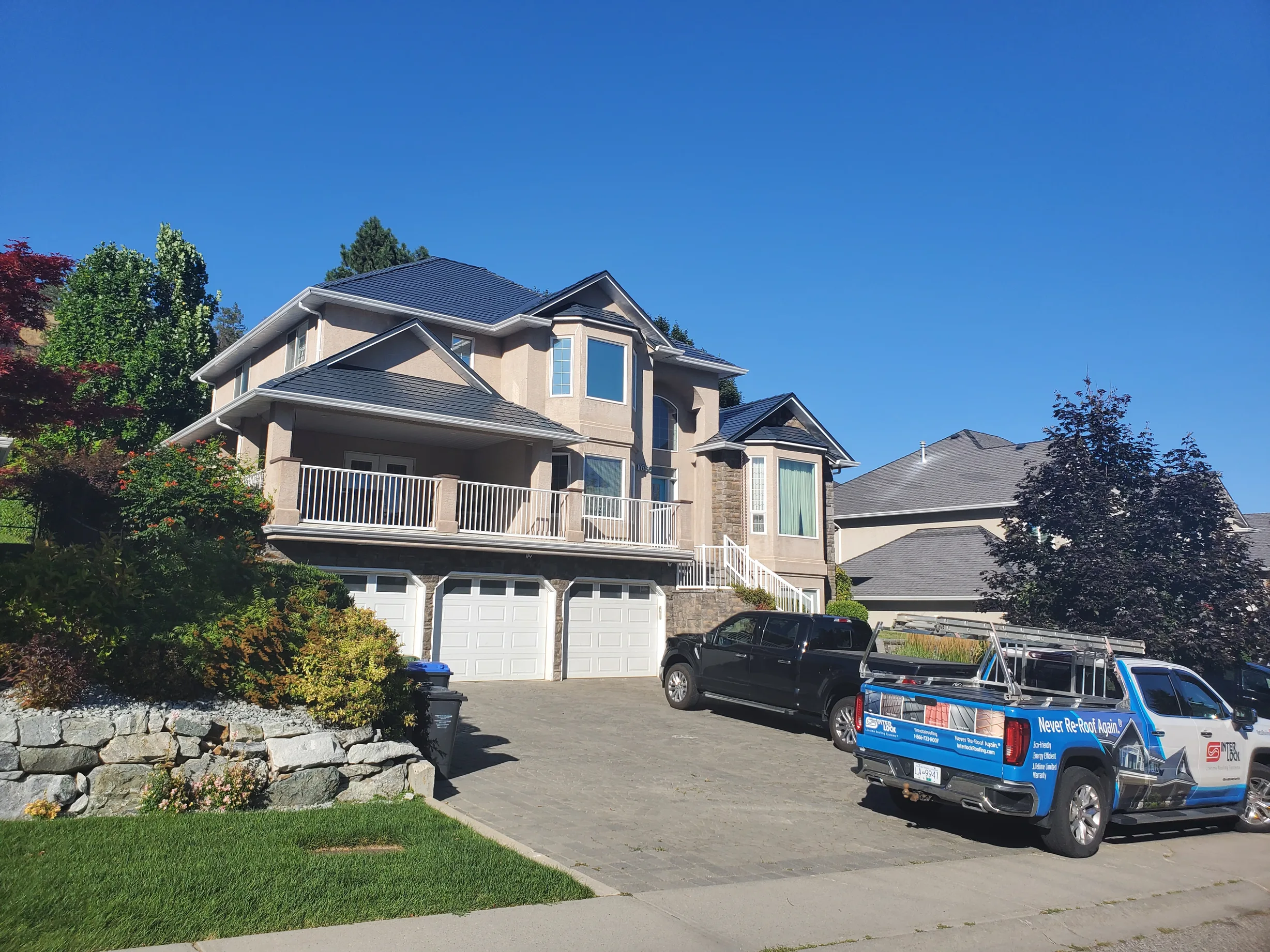 Deep Charcoal Interlock Slate aluminum roof on a tan two-storey home with a metal roof in a mountainous, Kelowna, British Columbia