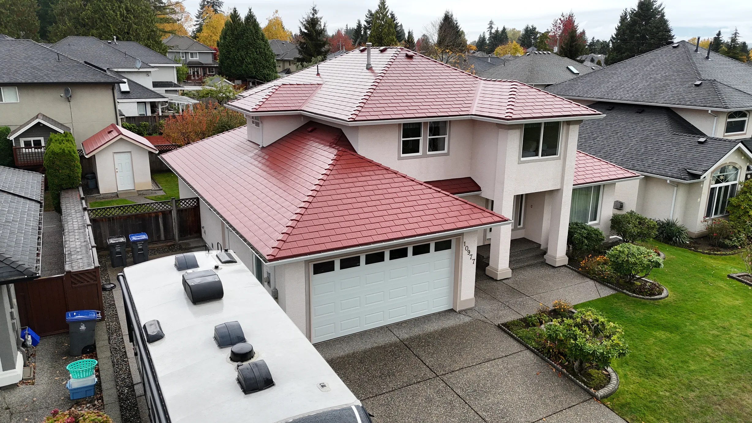 Tile Red Interlock Shingle aluminum roof on a two-storey white home with a red metal roof and a driveway, Surrey, British Columbia
