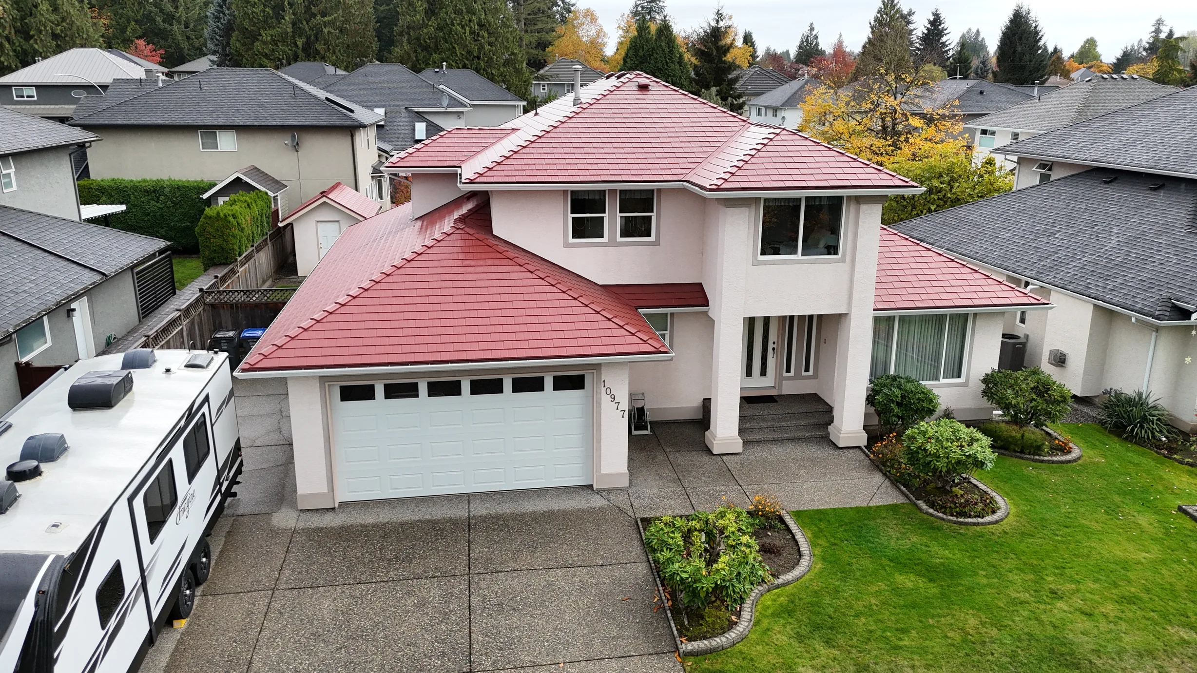 Tile Red Interlock Shingle aluminum roof on a two-storey home with red metal roof in a forested, Surrey, British Columbia
