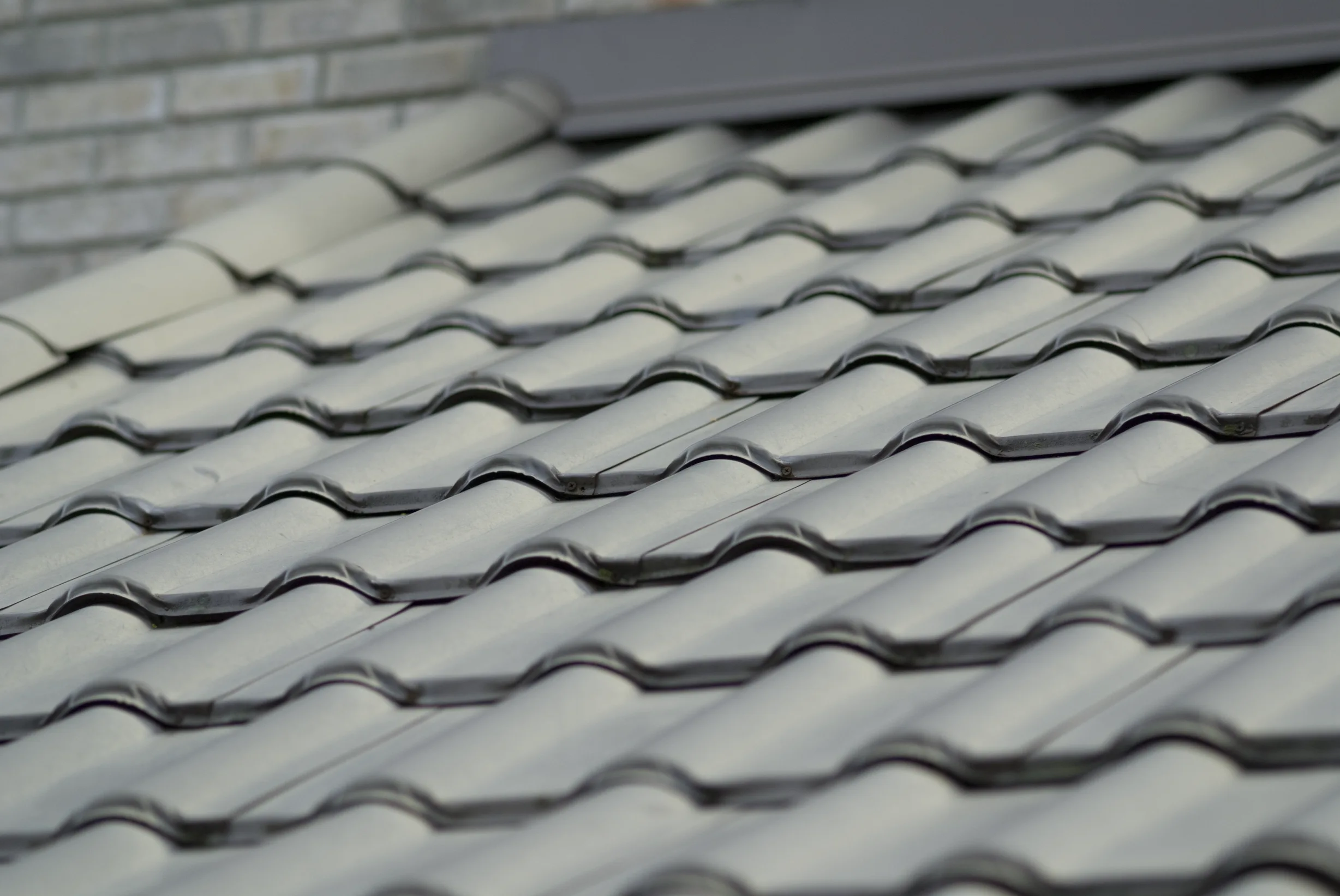 Before: a metal roof with broken tiles on the home, Surrey, British Columbia, ahead of a Black Interlock Slate aluminum roof