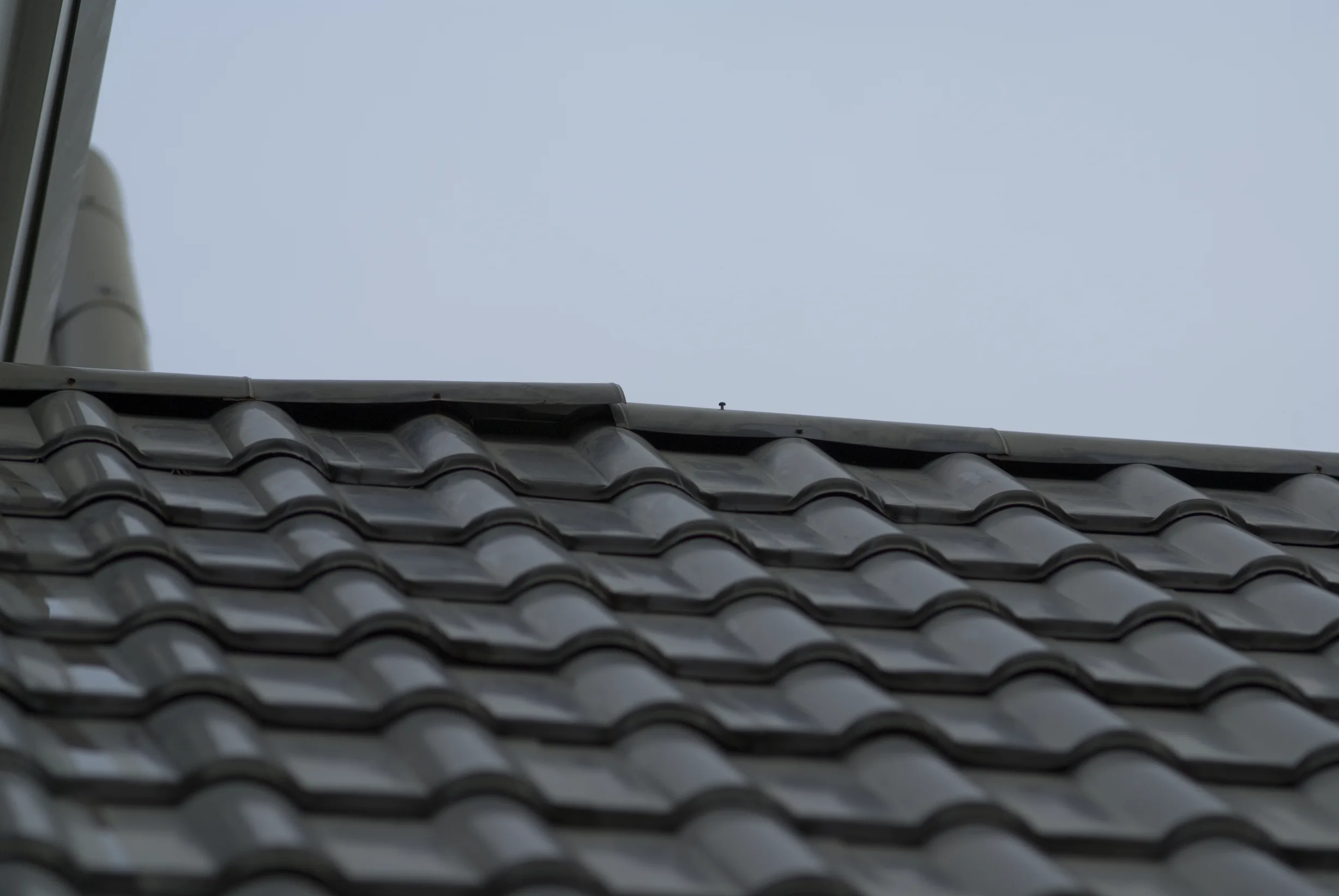 Before: a metal roof with broken tiles on the home, Surrey, British Columbia, ahead of a Black Interlock Slate aluminum roof