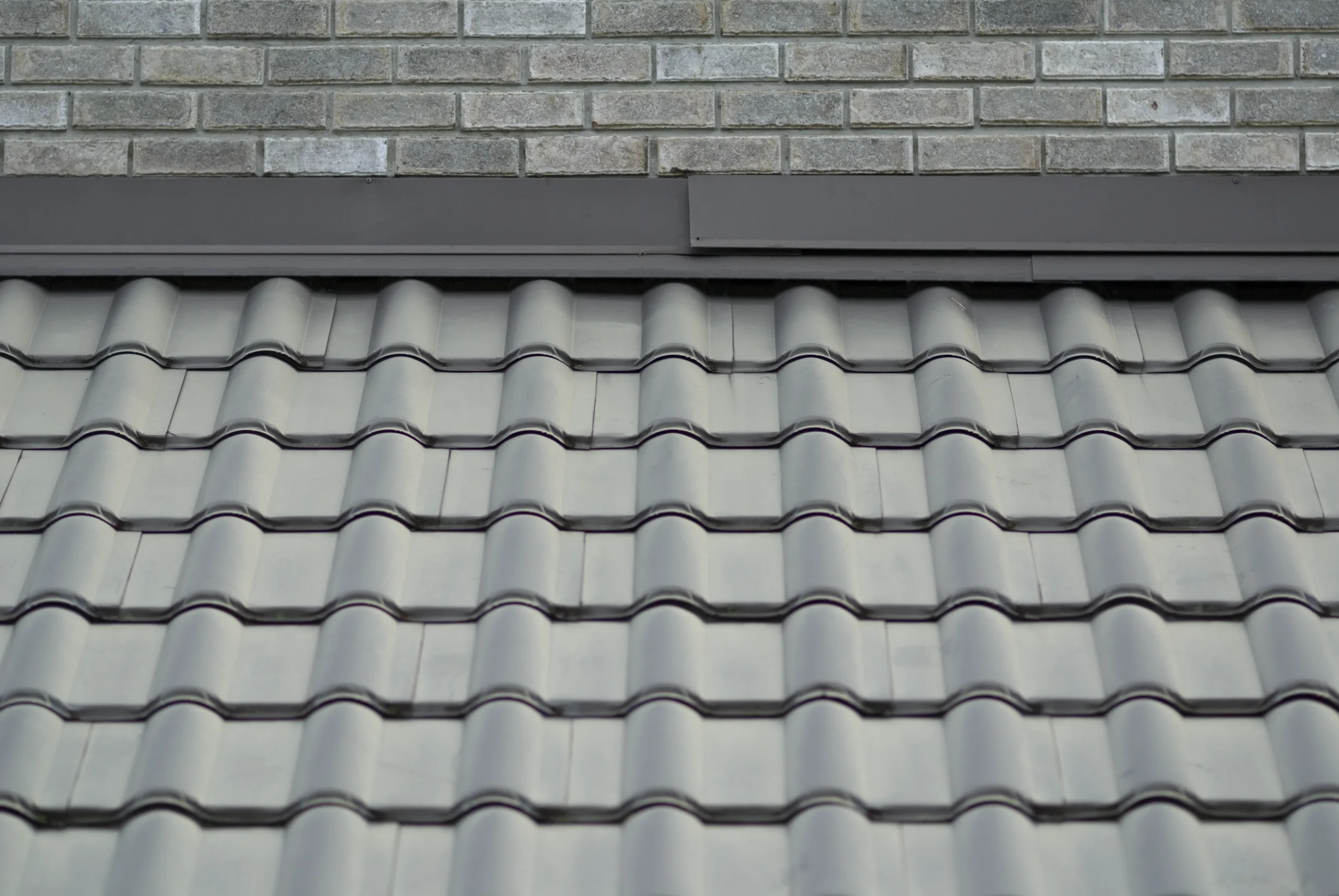 Before: a metal roof with broken tiles on the home, Surrey, British Columbia, ahead of a Black Interlock Slate aluminum roof