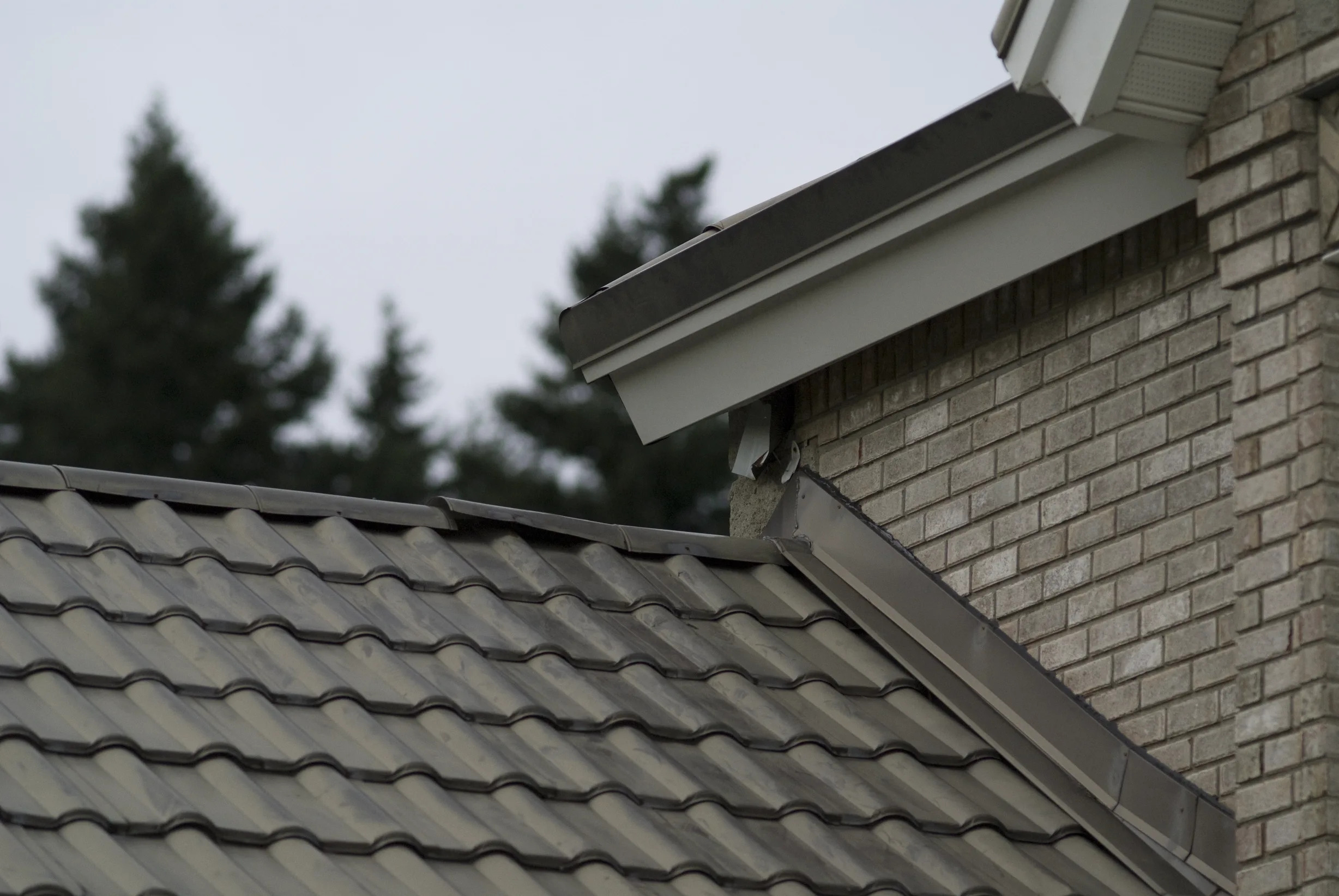 Before: a metal roof with broken tiles on the home, Surrey, British Columbia, ahead of a Black Interlock Slate aluminum roof