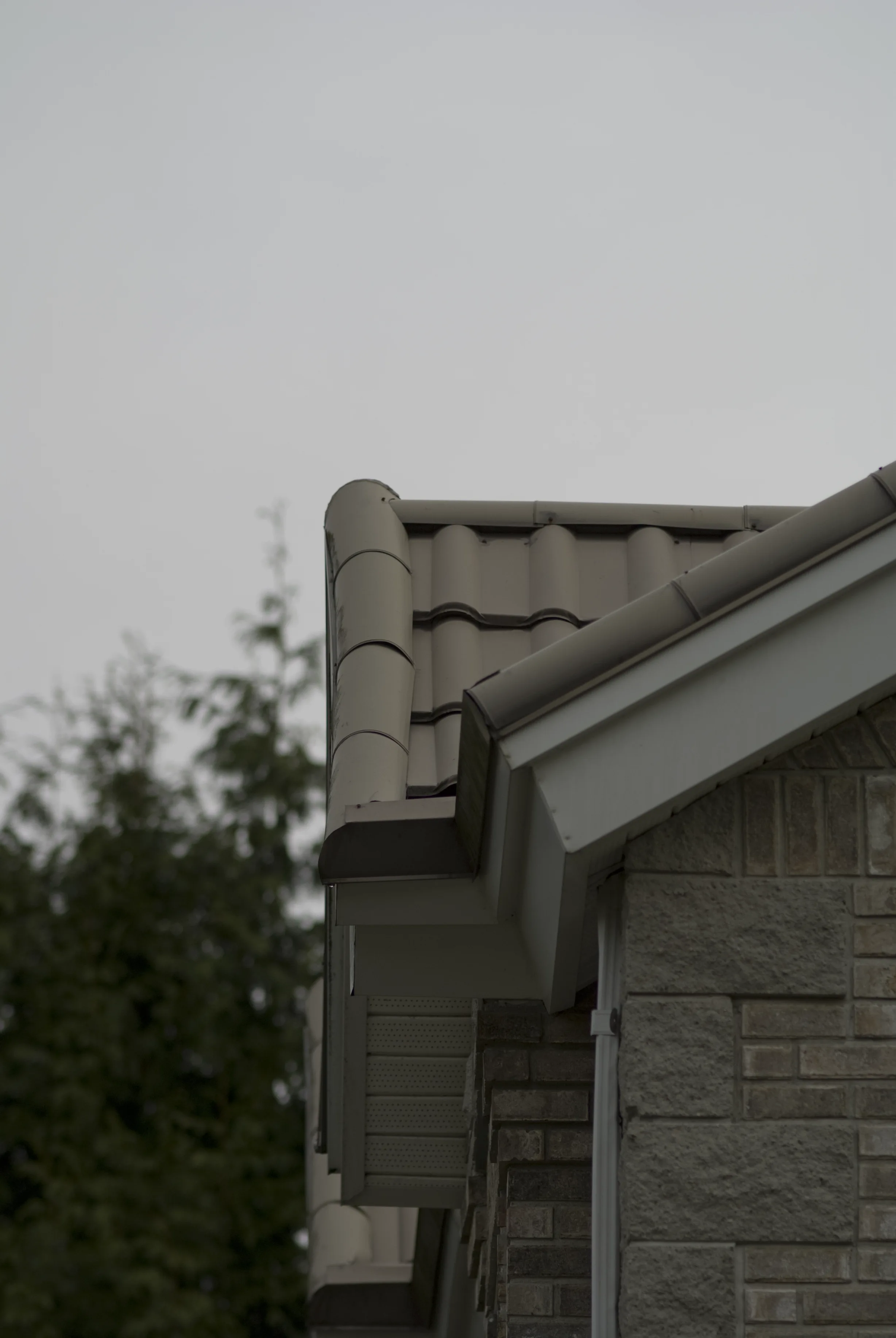 Before: a metal roof with broken tiles on the home, Surrey, British Columbia, ahead of a Black Interlock Slate aluminum roof