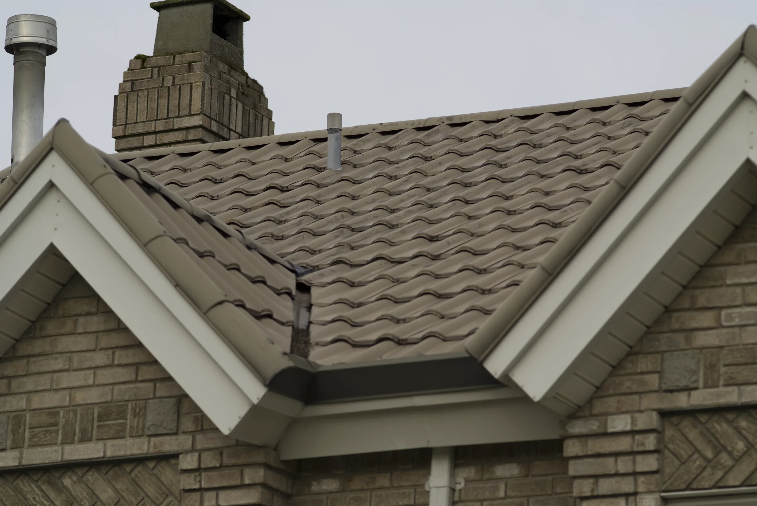 Before: a metal roof with broken tiles on the home, Surrey, British Columbia, ahead of a Black Interlock Slate aluminum roof