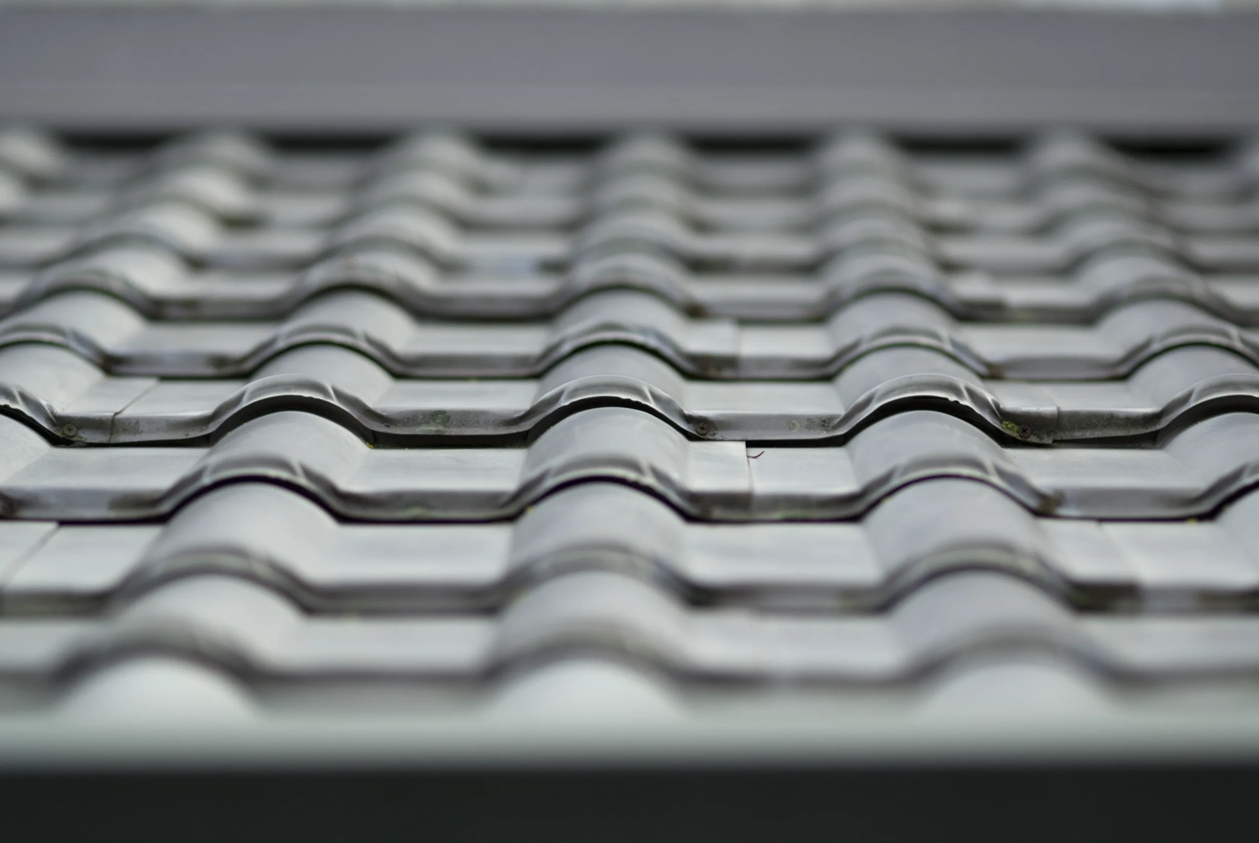 Before: a metal roof with broken tiles on the home, Surrey, British Columbia, ahead of a Black Interlock Slate aluminum roof