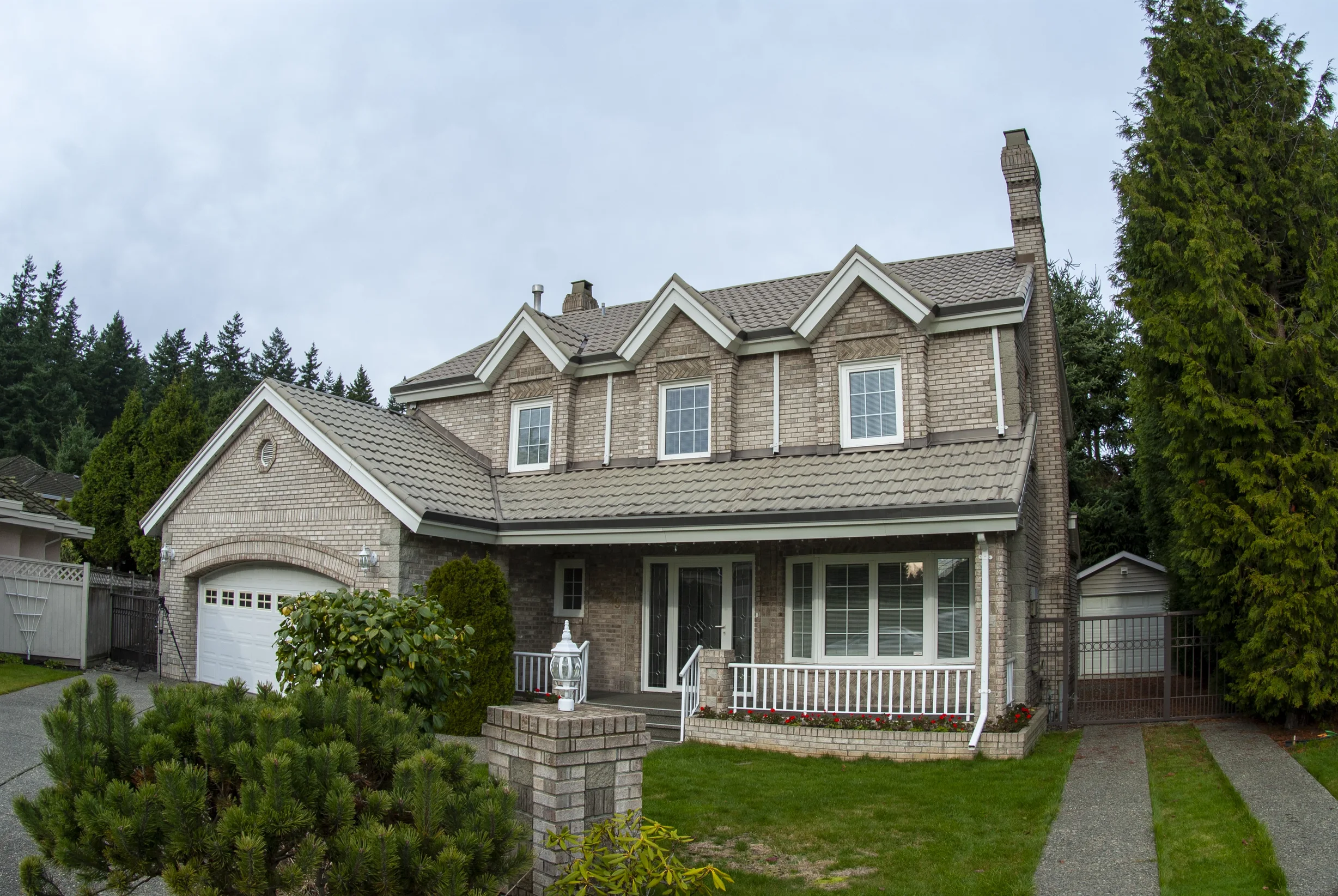 Before: a metal roof with broken tiles on the home, Surrey, British Columbia, ahead of a Black Interlock Slate aluminum roof