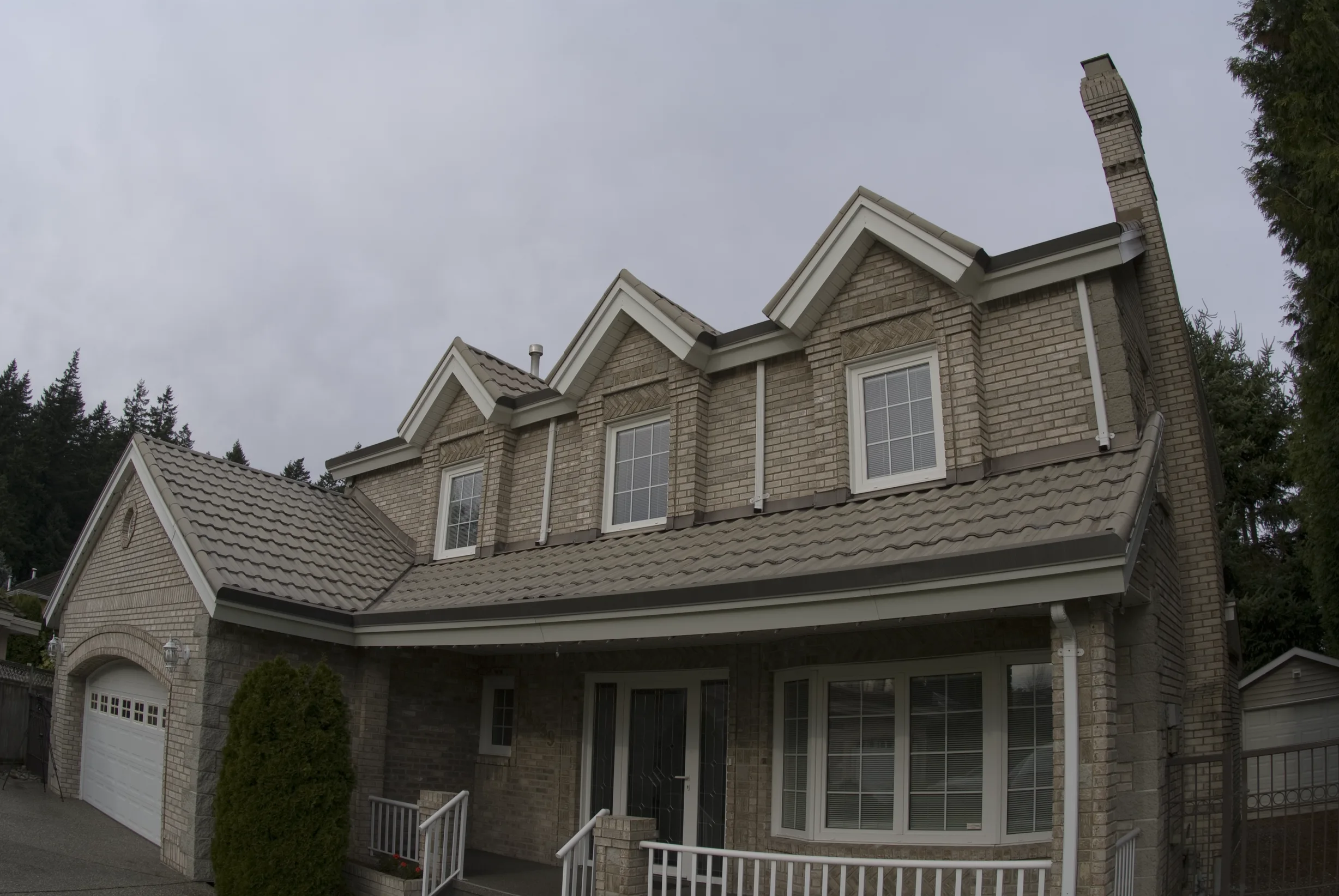 Before: a metal roof with broken tiles on the home, Surrey, British Columbia, ahead of a Black Interlock Slate aluminum roof
