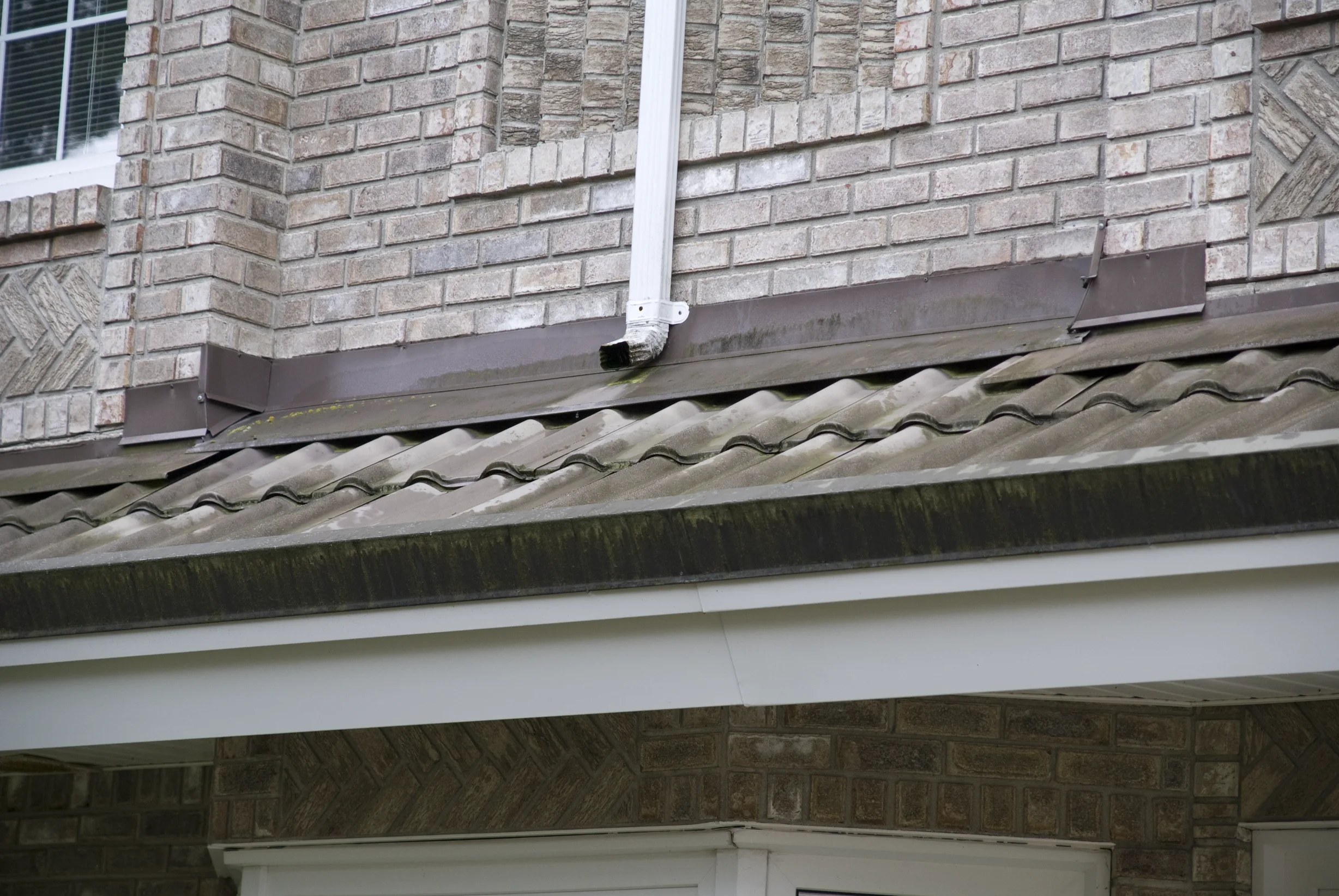Before: a metal roof with broken tiles on the home, Surrey, British Columbia, ahead of a Black Interlock Slate aluminum roof