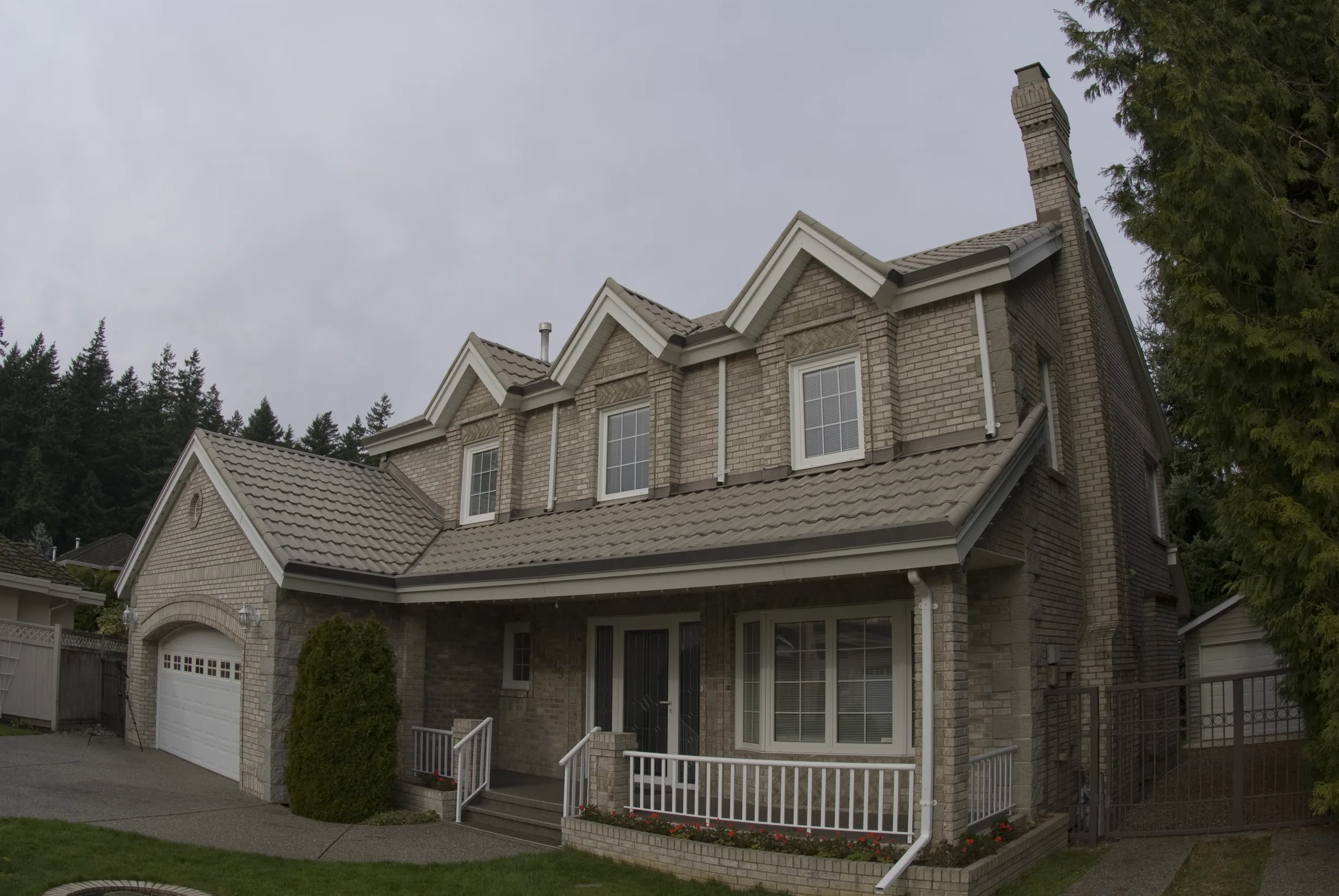 Before: a metal roof with broken tiles on the home, Surrey, British Columbia, ahead of a Black Interlock Slate aluminum roof