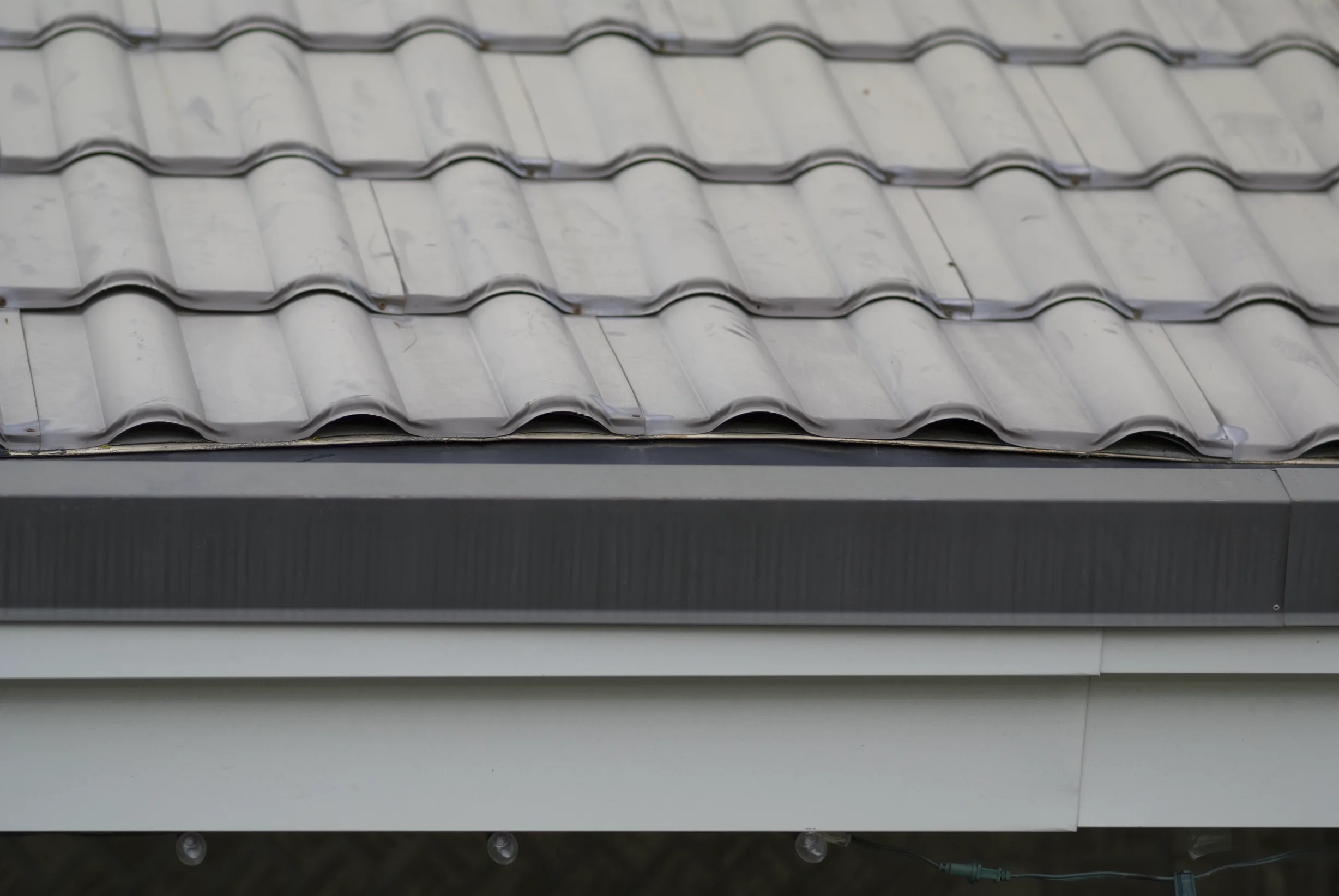 Before: a metal roof with broken tiles on the home, Surrey, British Columbia, ahead of a Black Interlock Slate aluminum roof