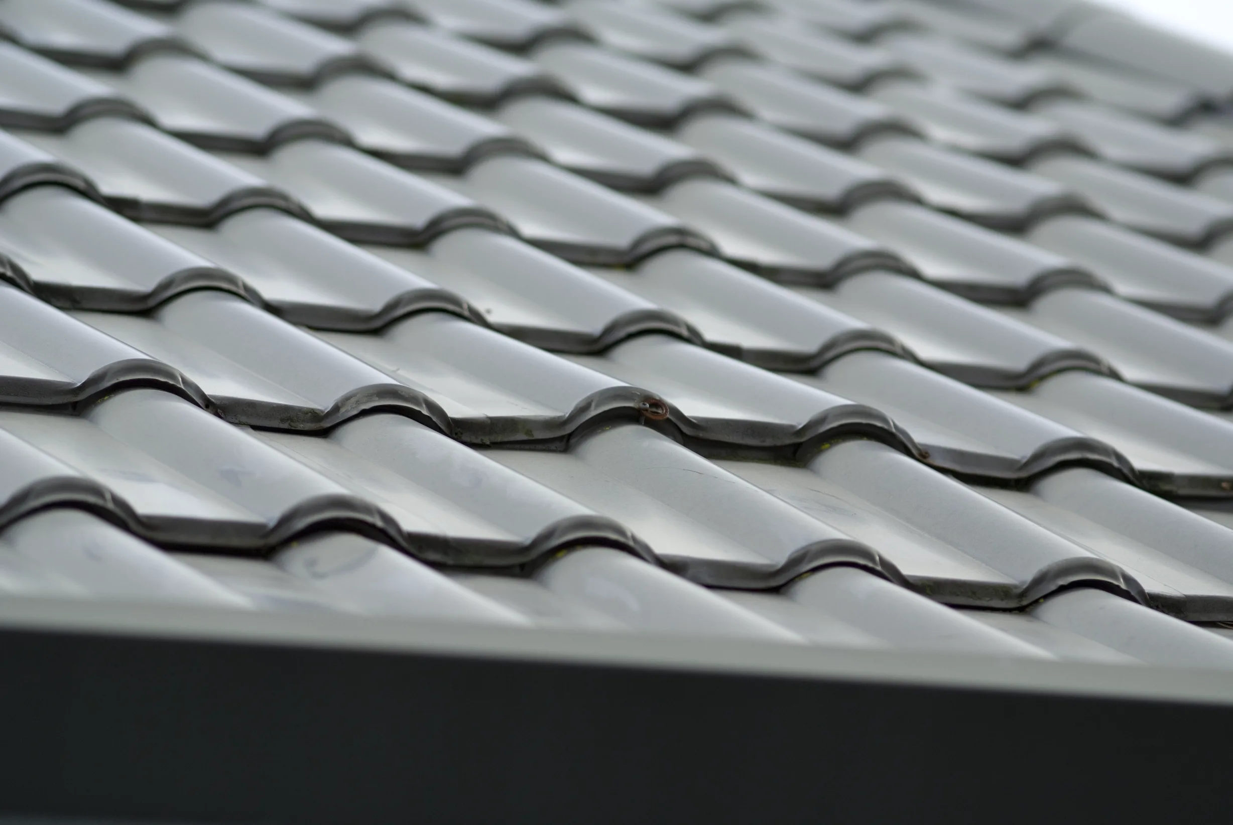 Before: a metal roof with broken tiles on the home, Surrey, British Columbia, ahead of a Black Interlock Slate aluminum roof