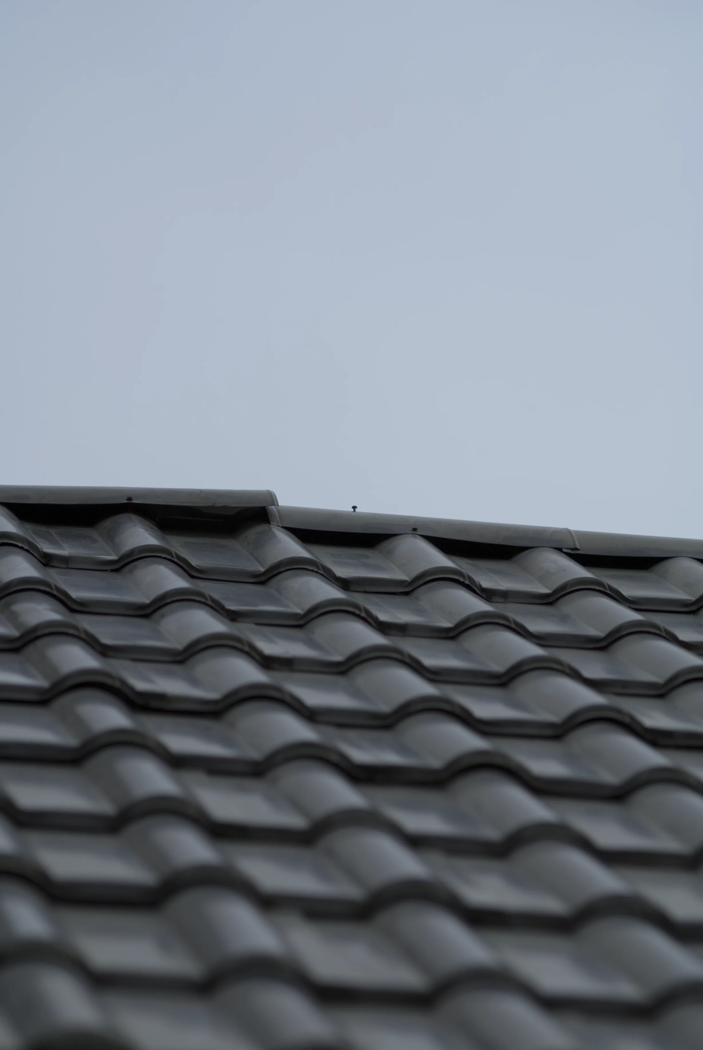 Before: a metal roof with broken tiles on the home, Surrey, British Columbia, ahead of a Black Interlock Slate aluminum roof