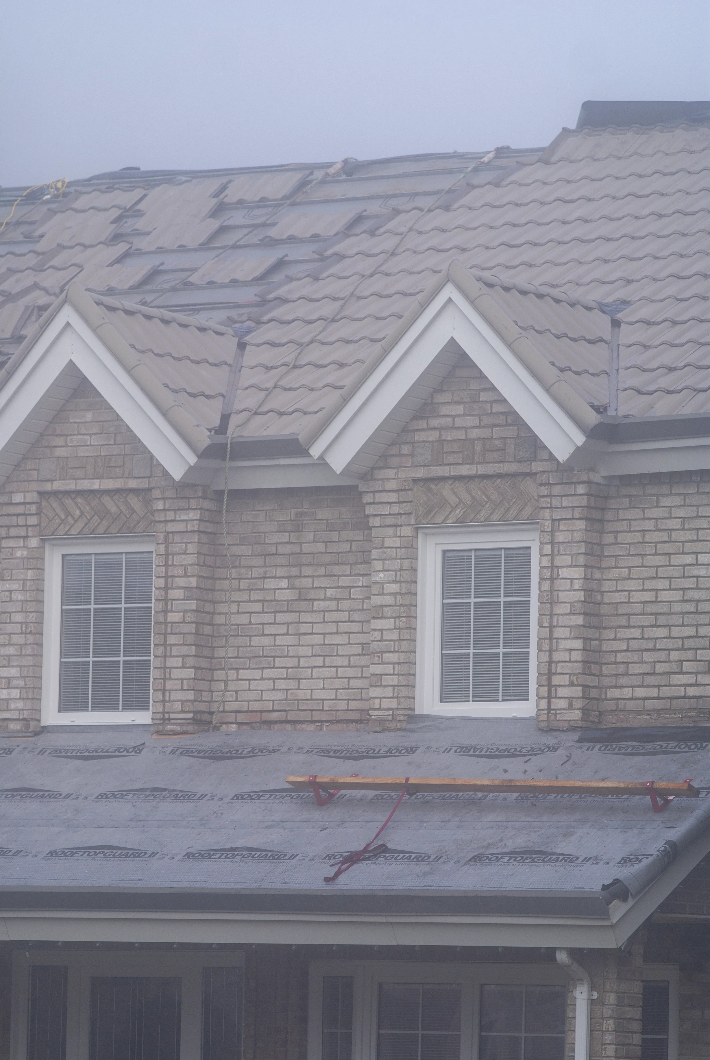 Black Interlock Slate aluminum roof on a tan house with a brown metal roof and white trim in a, Surrey, British Columbia