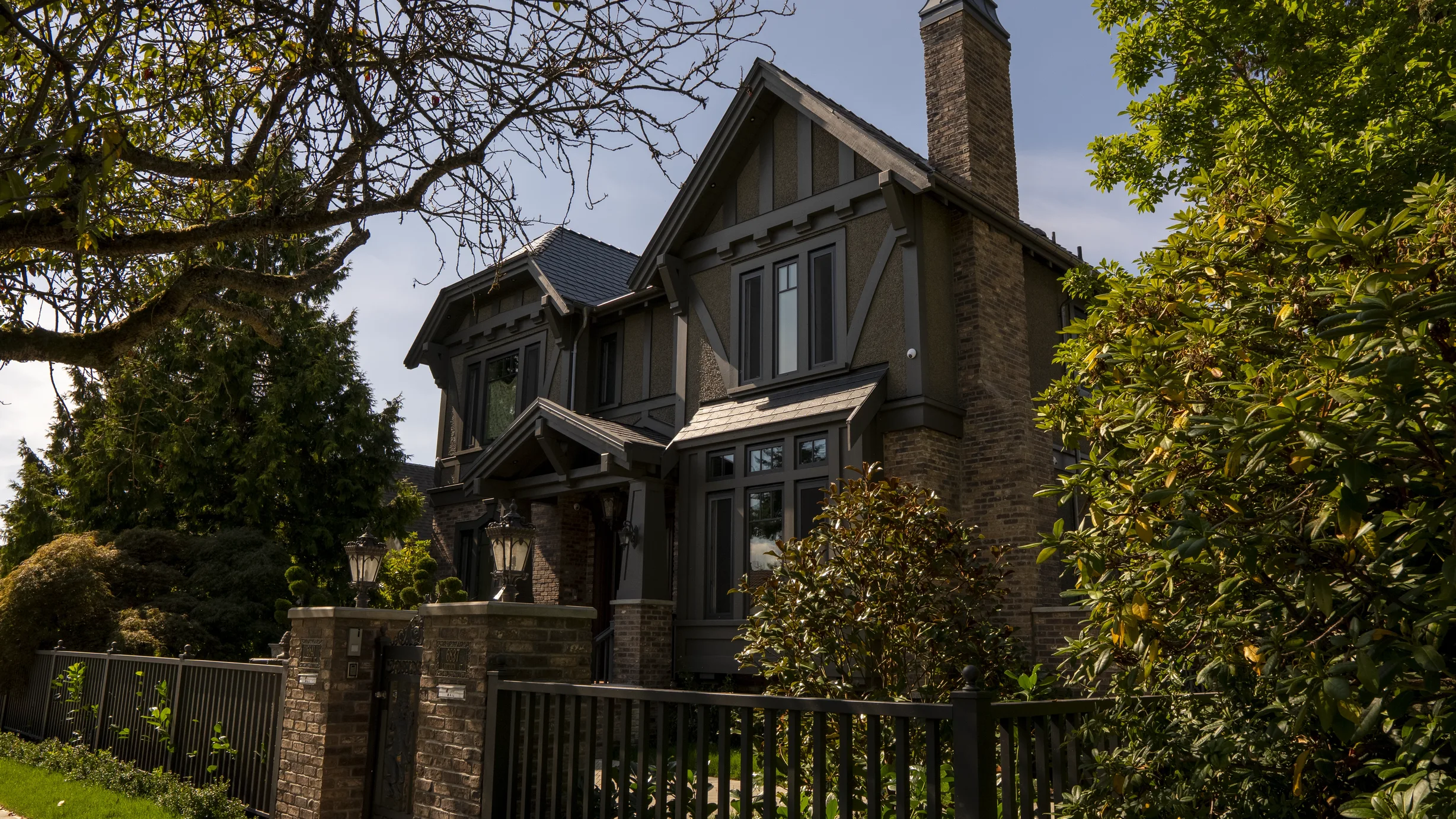 Deep Charcoal Interlock Slate aluminum roof on a brown two-storey craftsman home with dormers among tall, Vancouver, British Columbia