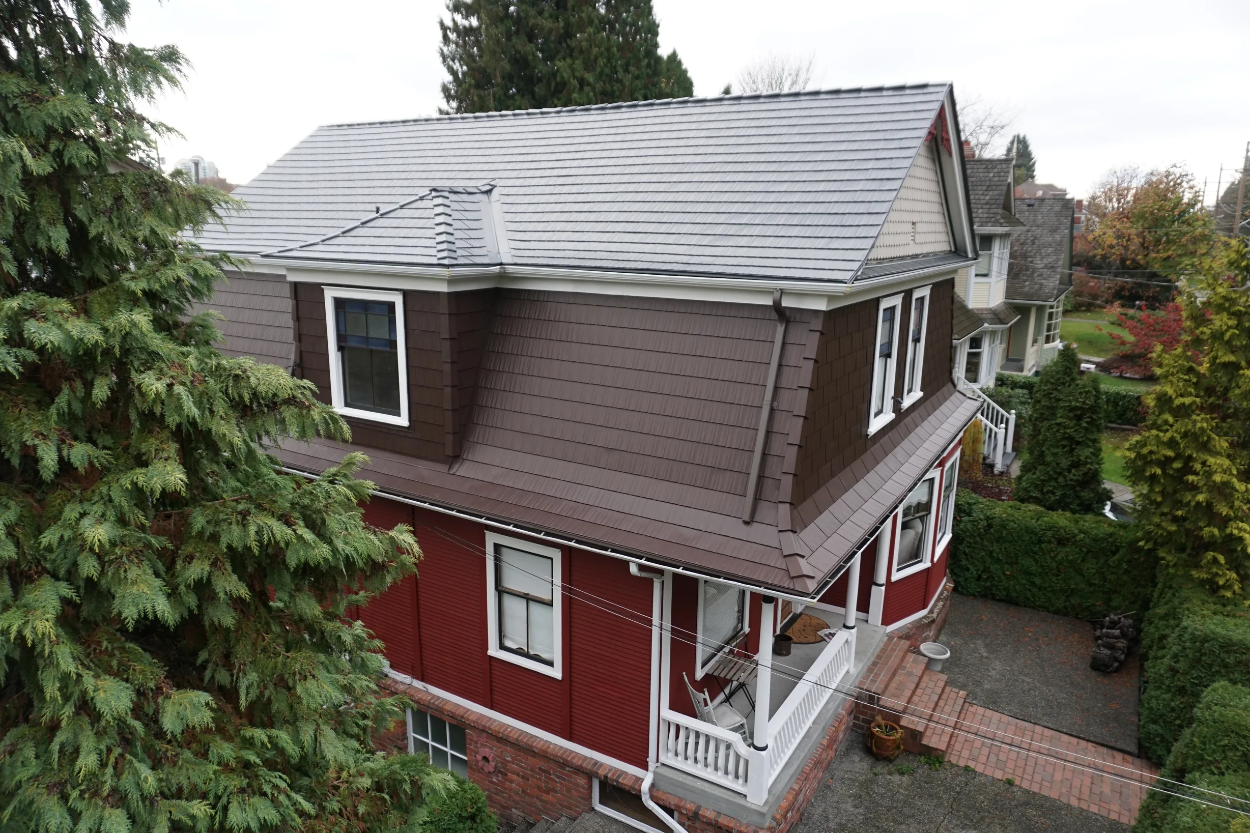 Colonial Brown Interlock Cedar Shingle aluminum roof on a red two-storey home with Colonial style in an urban area, New Westminster, British Columbia