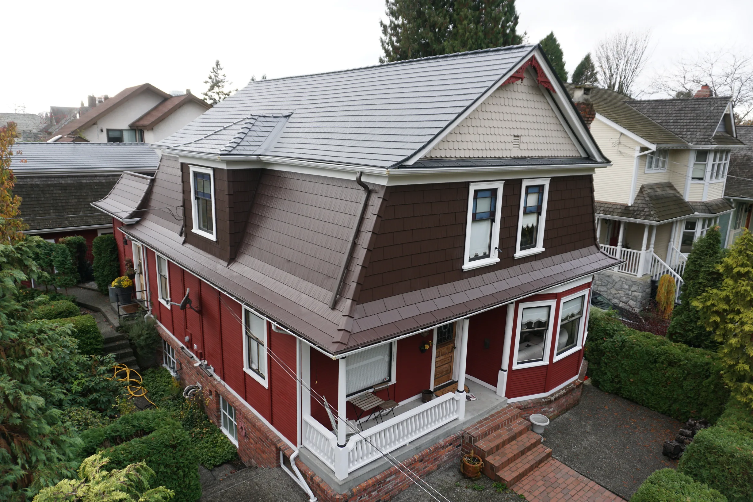 Colonial Brown Interlock Cedar Shingle aluminum roof on a former PNE Prize home, a red two-storey home with dormers near Queens Park in New Westminster, BC.