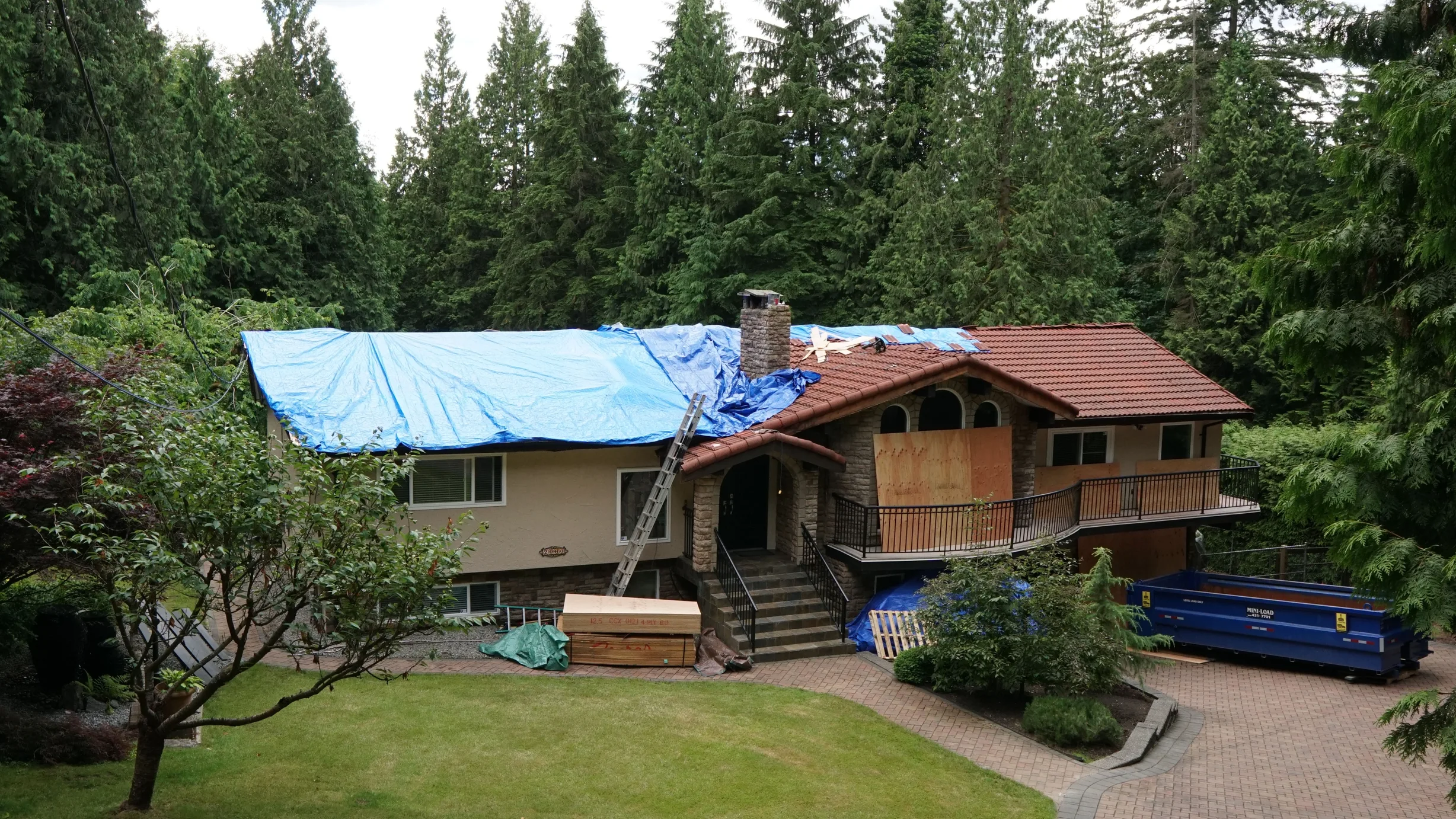 Deep Charcoal Interlock Slate aluminum roof on a brown chalet-style home with a metal roof in the forest, Anmore, British Columbia