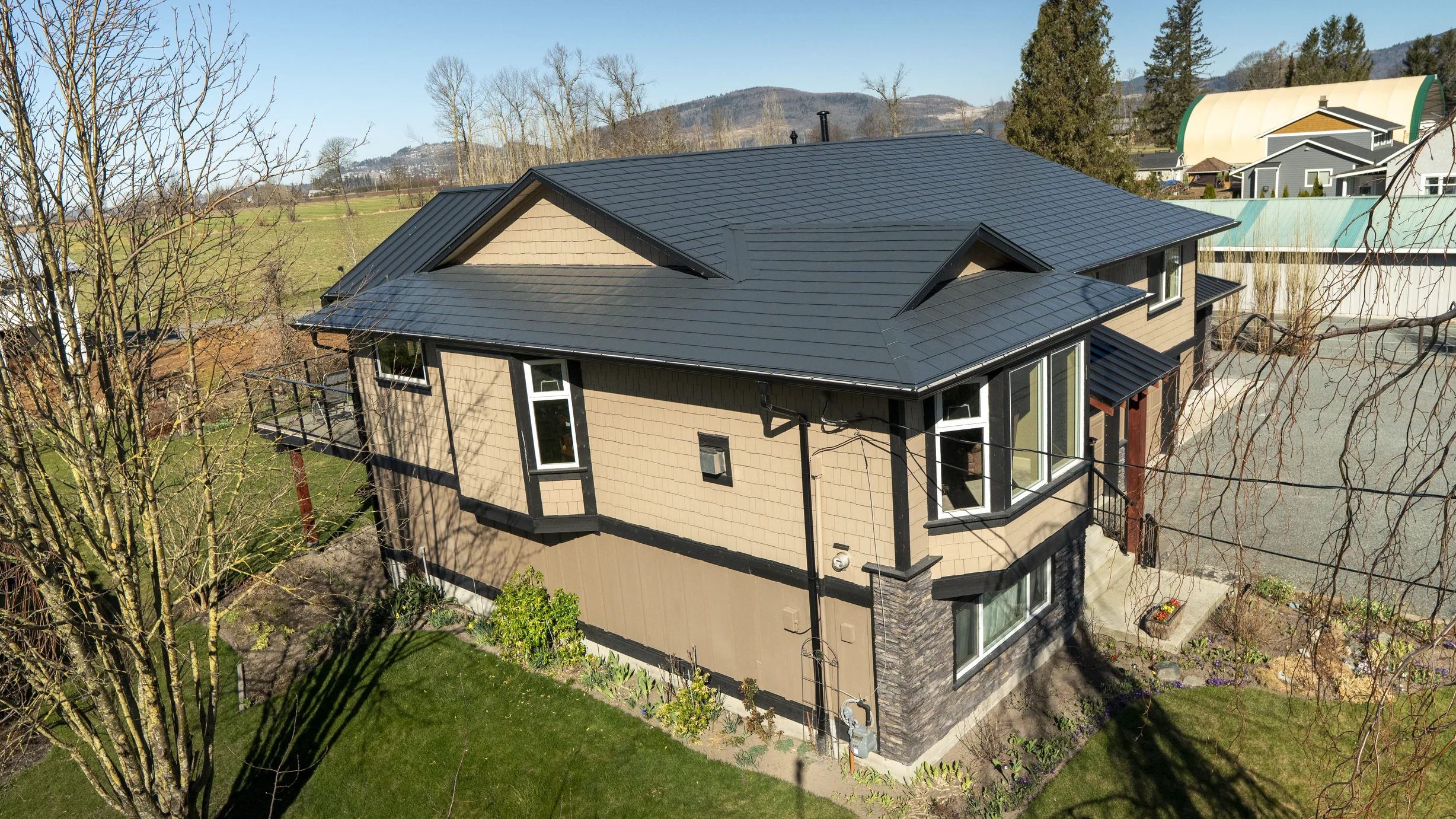 Deep Charcoal Interlock Slate aluminum roof on a tan single-family home with a metal roof in a rural, Abbotsford, British Columbia