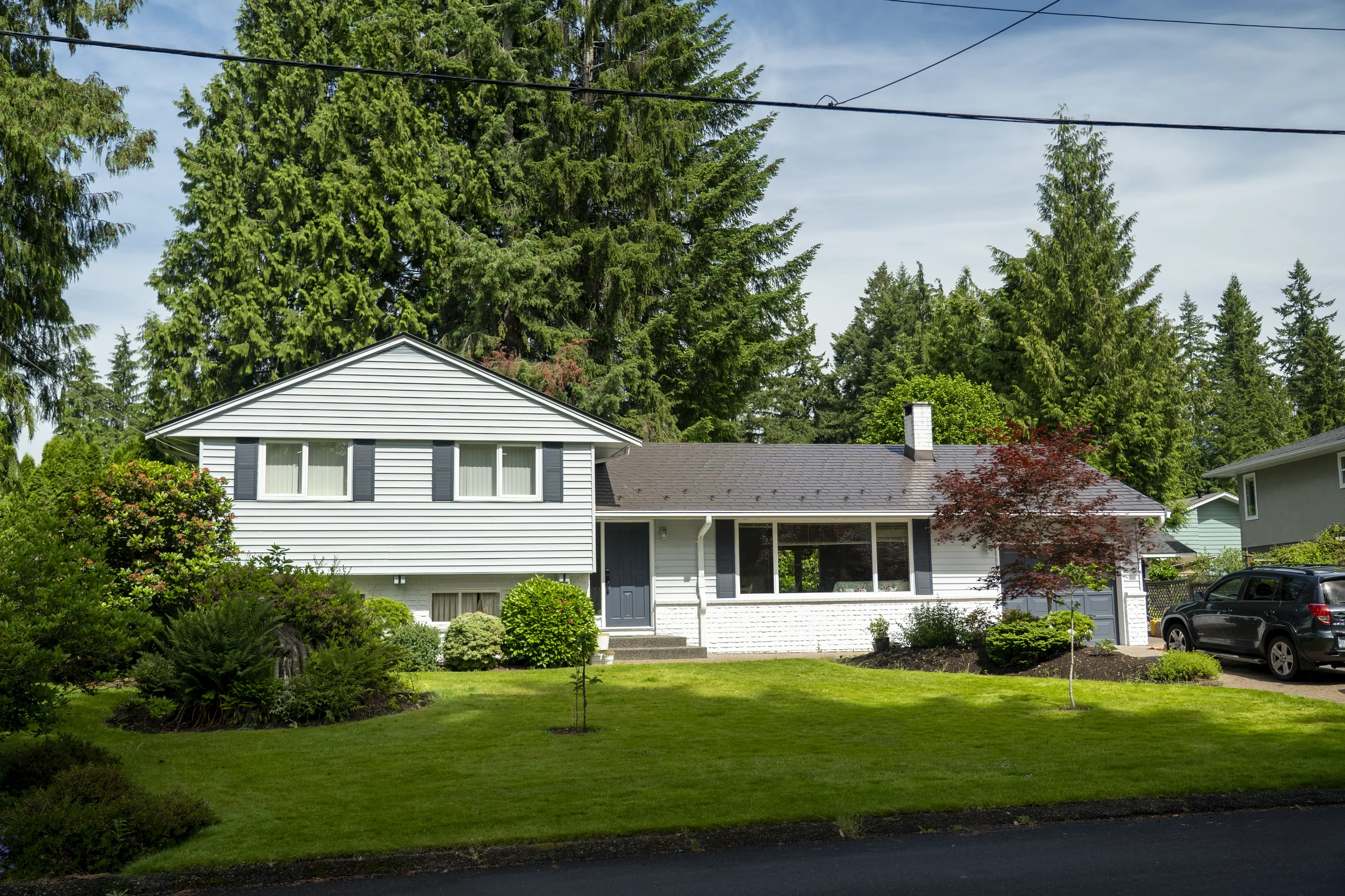 Tudor Brown Interlock Slate aluminum roof on a two-storey Tudor brown metal roofed home in a forested, North Vancouver, British Columbia