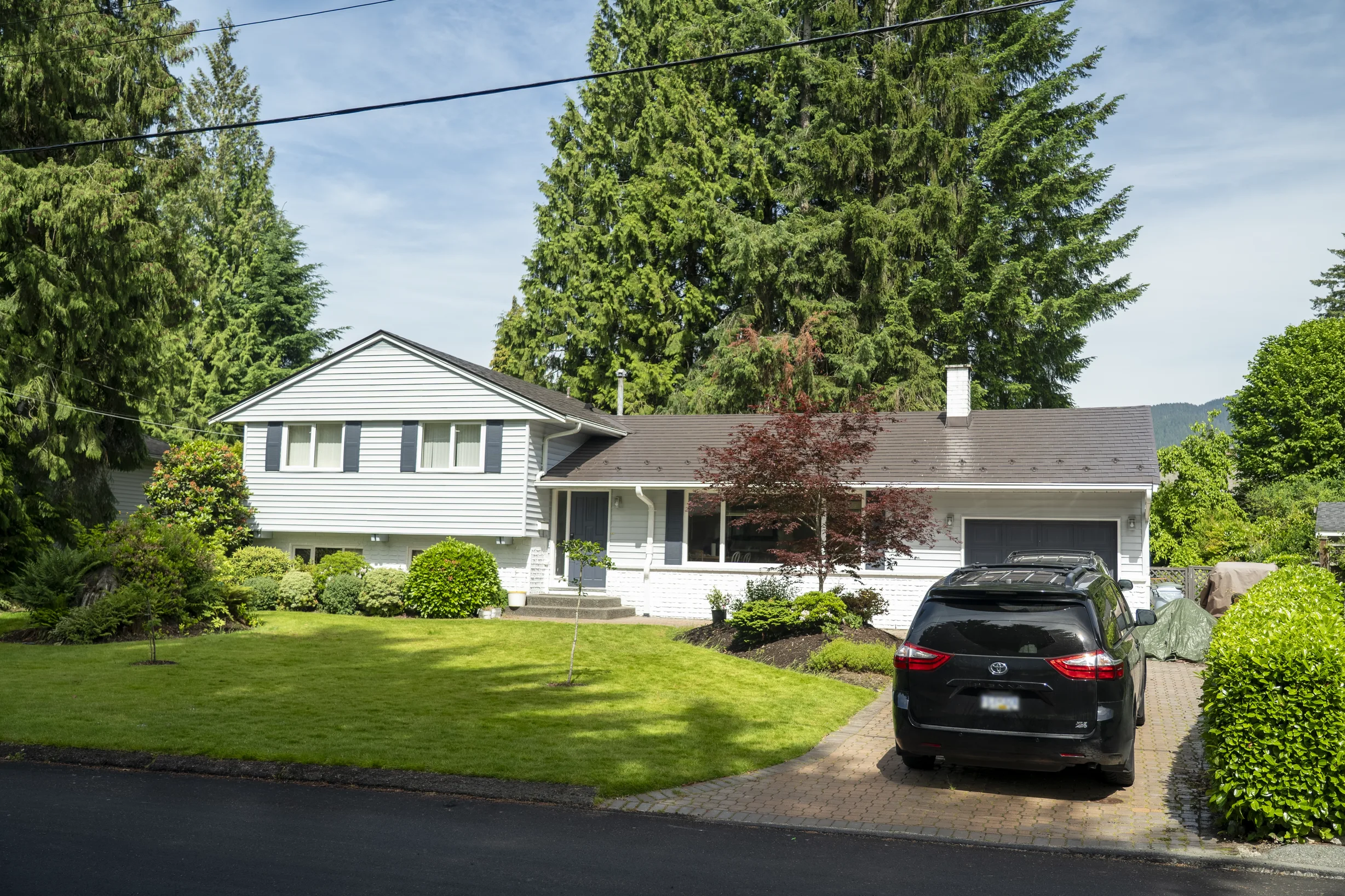 Tudor Brown Interlock Slate aluminum roof on a white Tudor home with dormers in a suburban mountain, North Vancouver, British Columbia