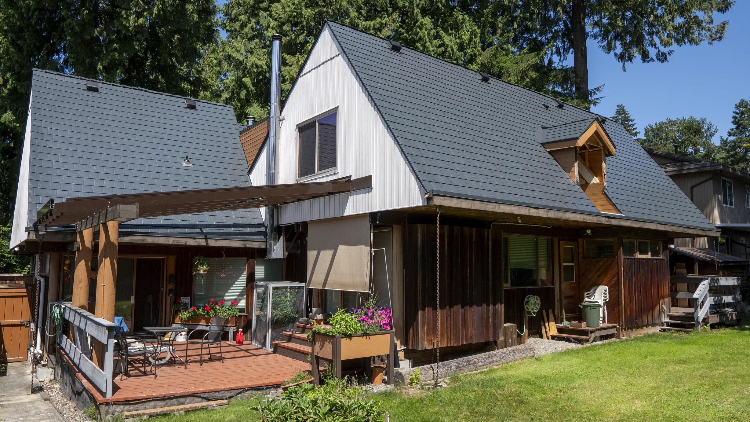 Deep Charcoal Interlock Slate aluminum roof on a white A-frame home with dormers among tall trees, Burnaby, British Columbia