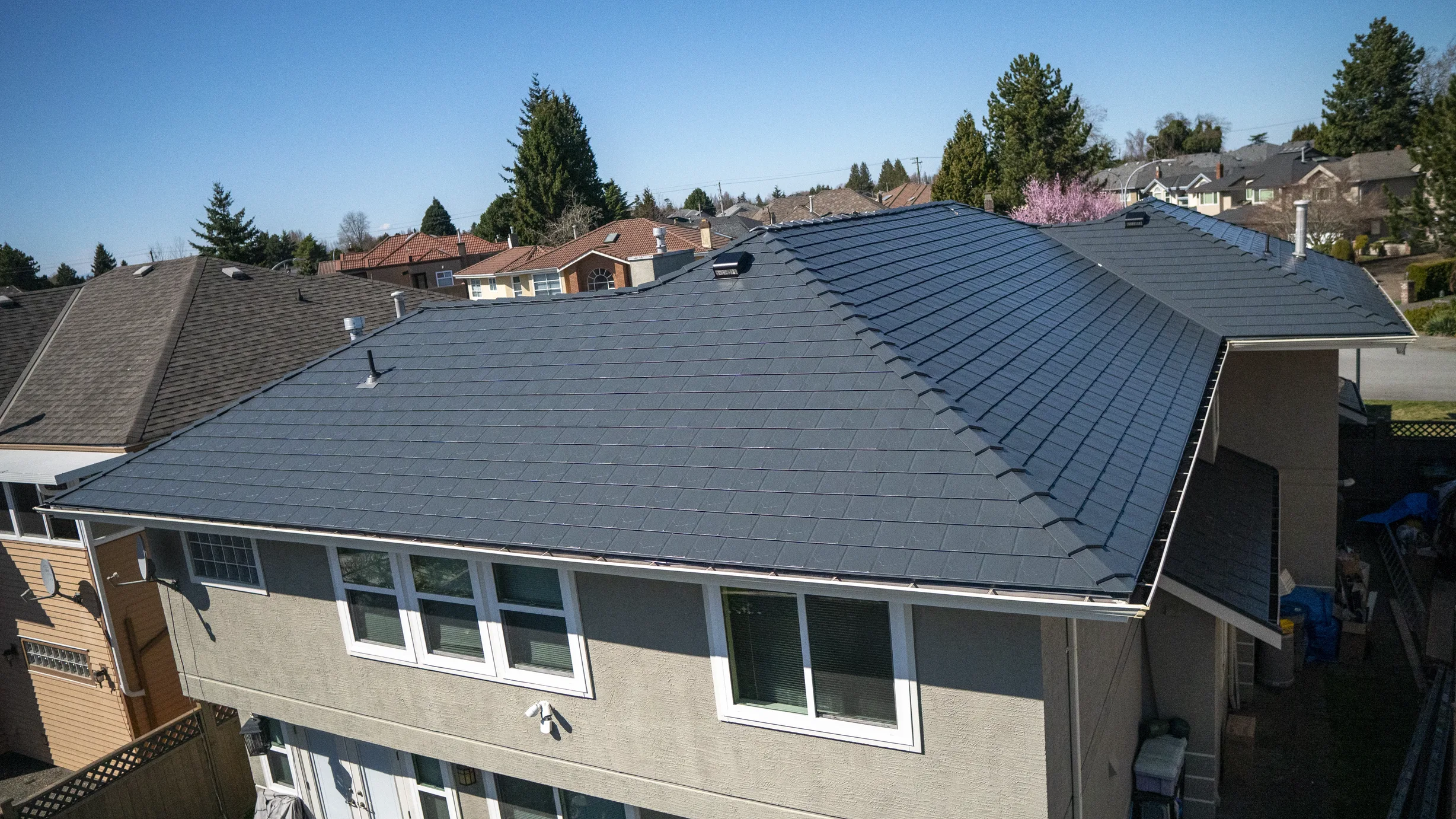 Deep Charcoal Interlock Slate aluminum roof on a beige home with a metal roof in an urban setting, Richmond, British Columbia
