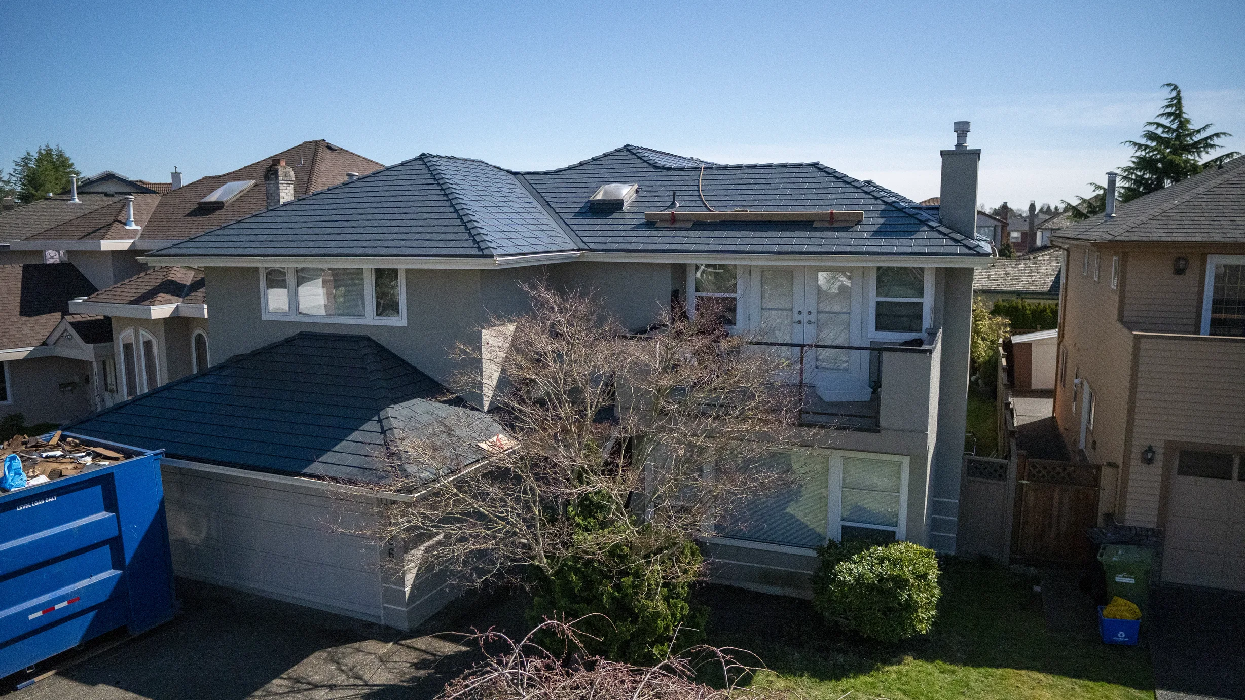 Deep Charcoal Interlock Slate aluminum roof on a grey single-family home with a balcony in a suburban, Richmond, British Columbia