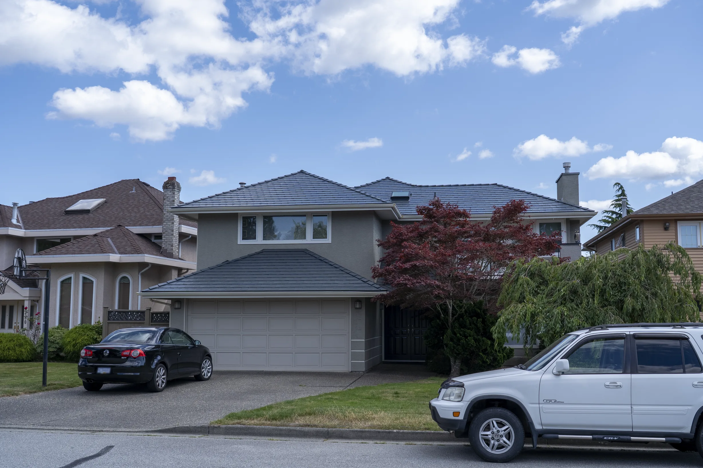 Deep Charcoal Interlock Slate aluminum roof on a beige two-storey home with dormers in a suburban, Richmond, British Columbia