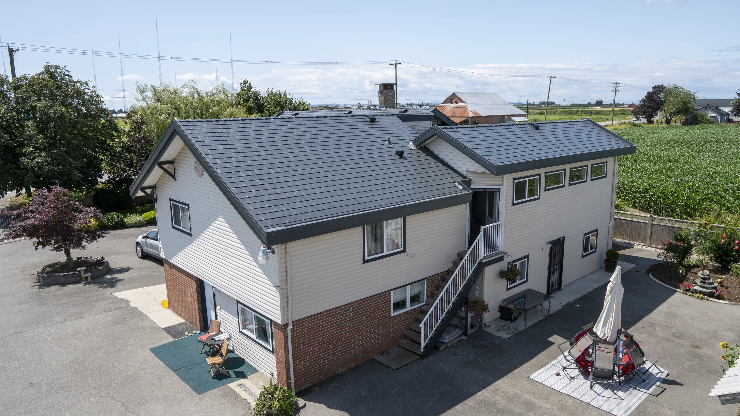Deep Charcoal Interlock Slate aluminum roof on a two-storey home with dormers in a rural setting, Delta, British Columbia