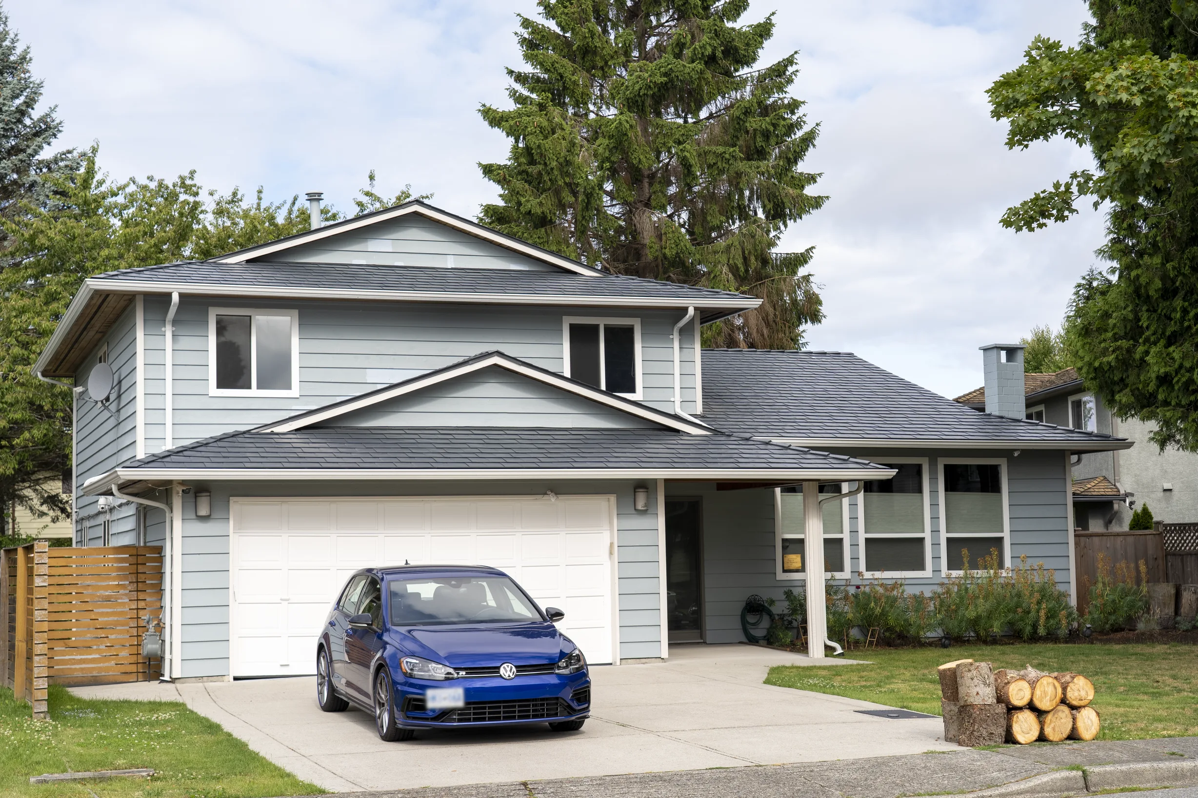Deep Charcoal Interlock Slate aluminum roof on a gray two-storey home with a metal roof in a forested, Richmond, British Columbia