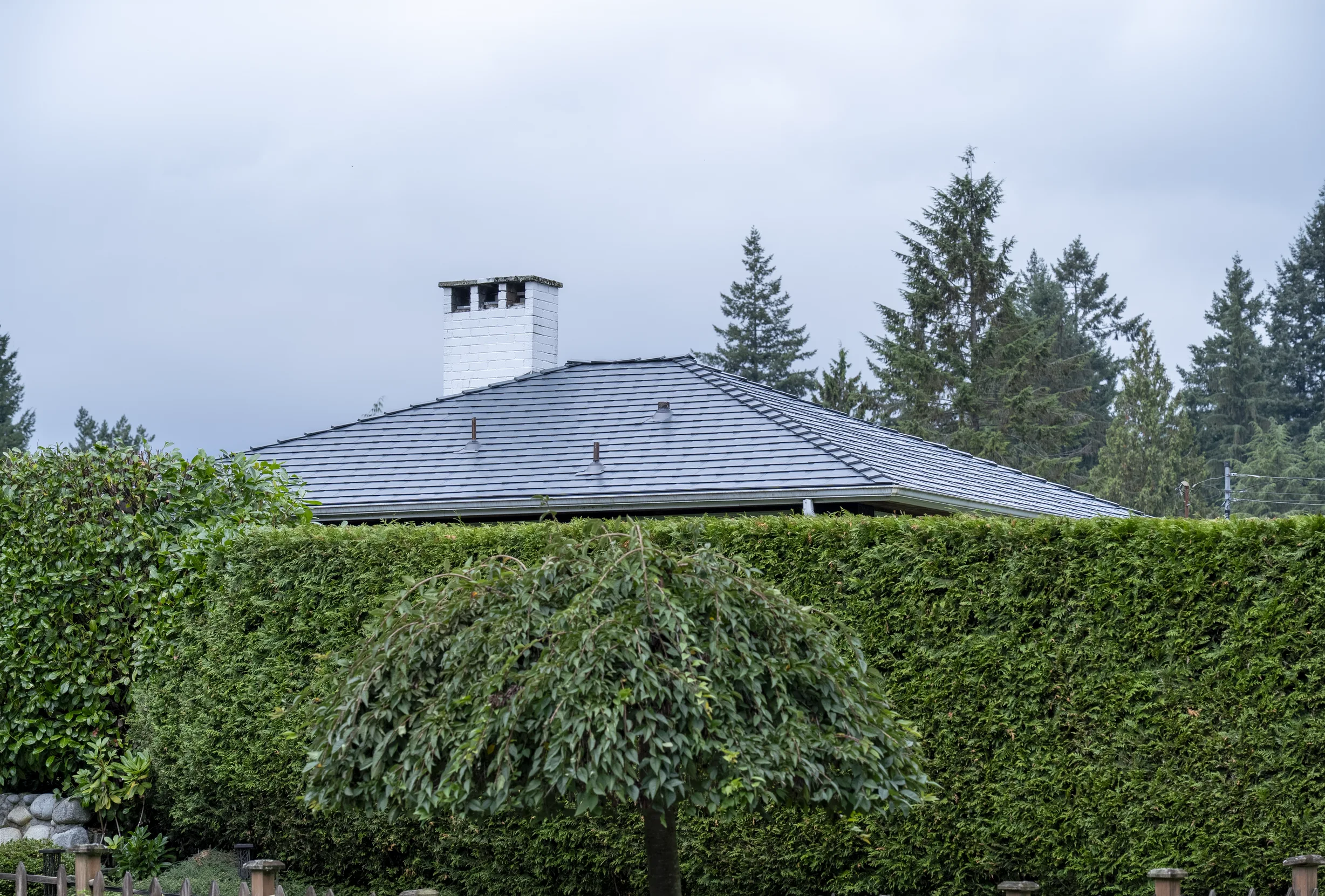 Deep Charcoal Interlock Slate aluminum roof on a Deep Charcoal metal roof on a house in a forested area, North Vancouver, British Columbia
