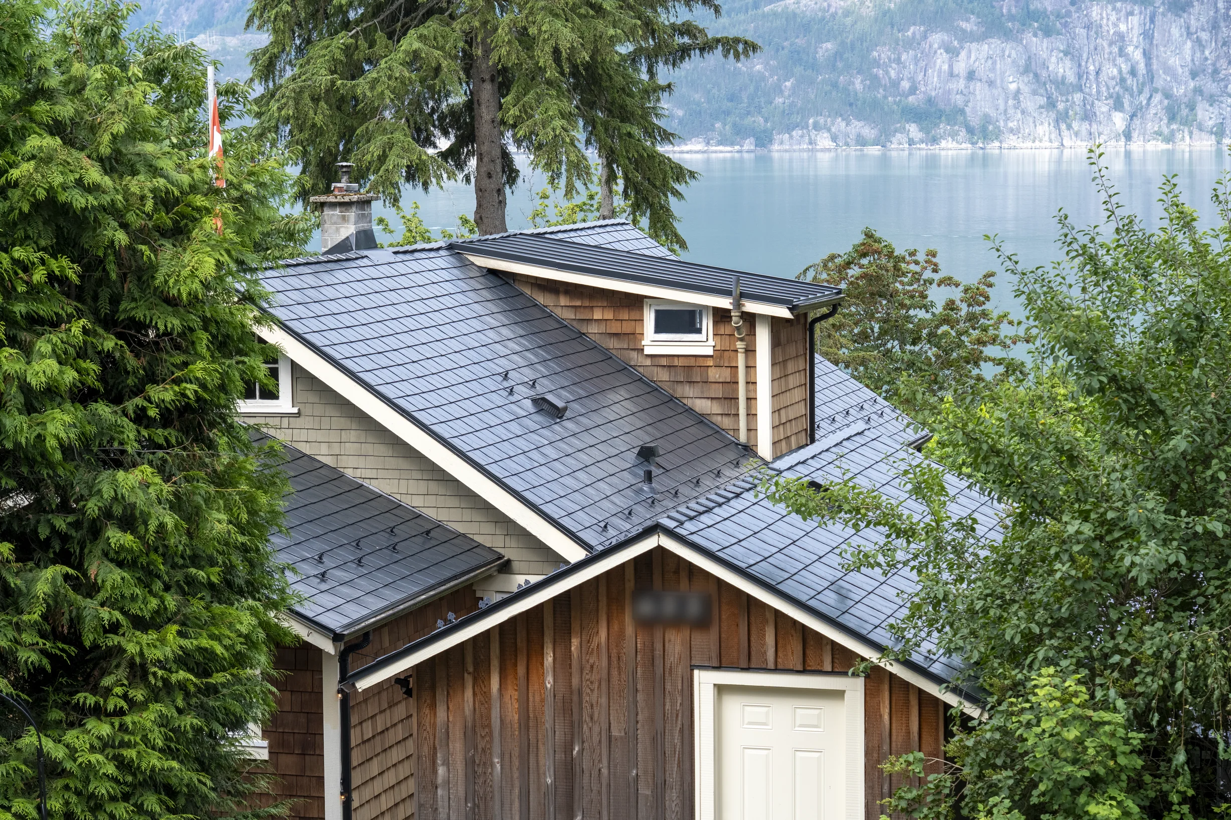 Black Interlock Slate aluminum roof on a brown house with a metal roof on the waterfront in a, Britannia Beach, British Columbia