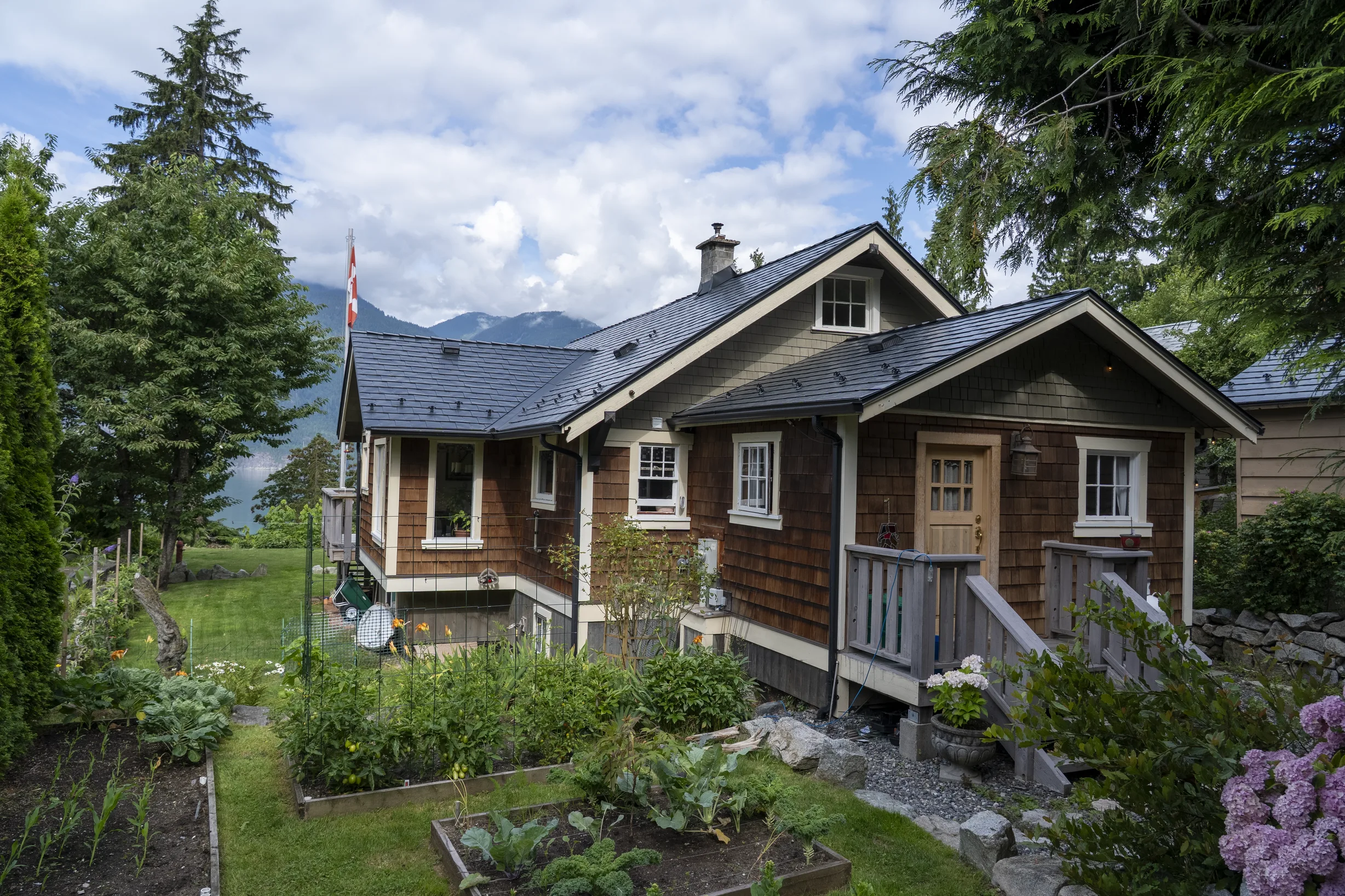 Black Interlock Slate aluminum roof on a brown cottage with a dark metal roof in a lush green, Britannia Beach, British Columbia