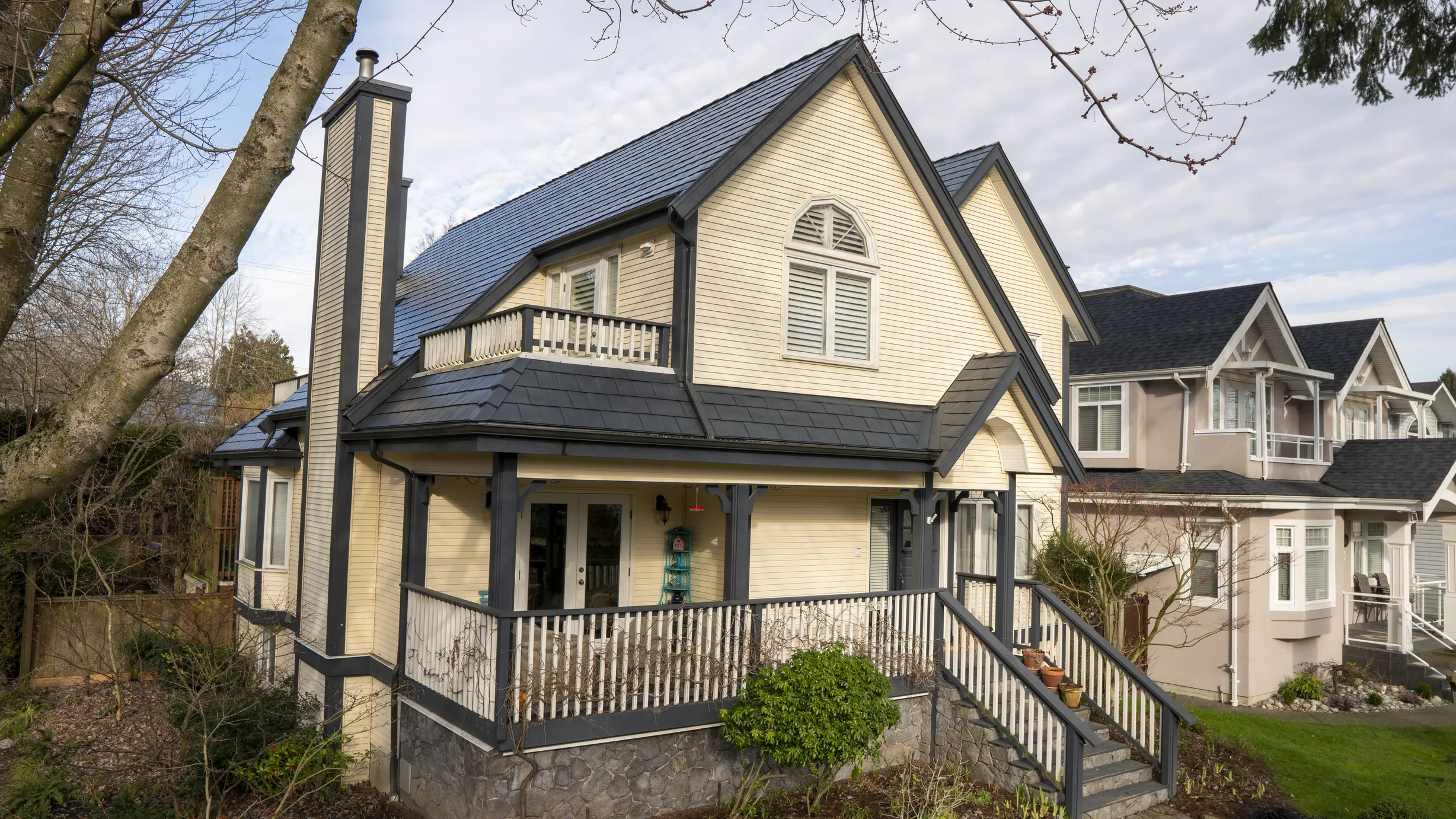 Deep Charcoal Interlock Slate aluminum roof on a two-storey cream home with a gable roof in a suburban, Vancouver, British Columbia