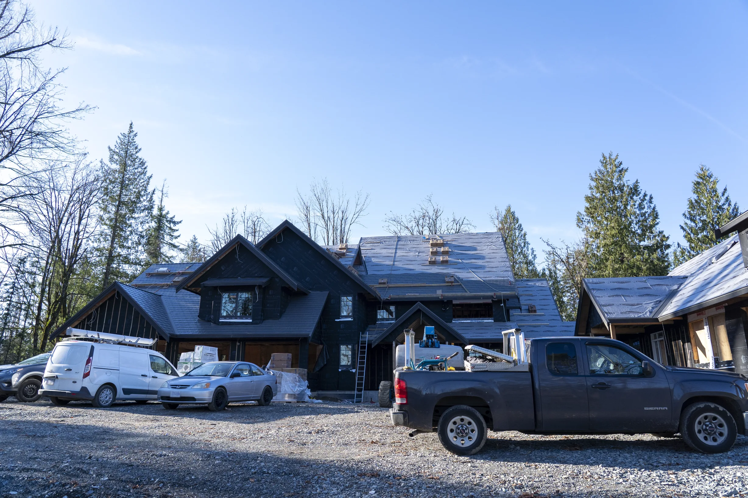 Musket Grey Interlock Slate aluminum roof being installed on a modern home with a metal roof in a forest setting, Abbotsford, British Columbia