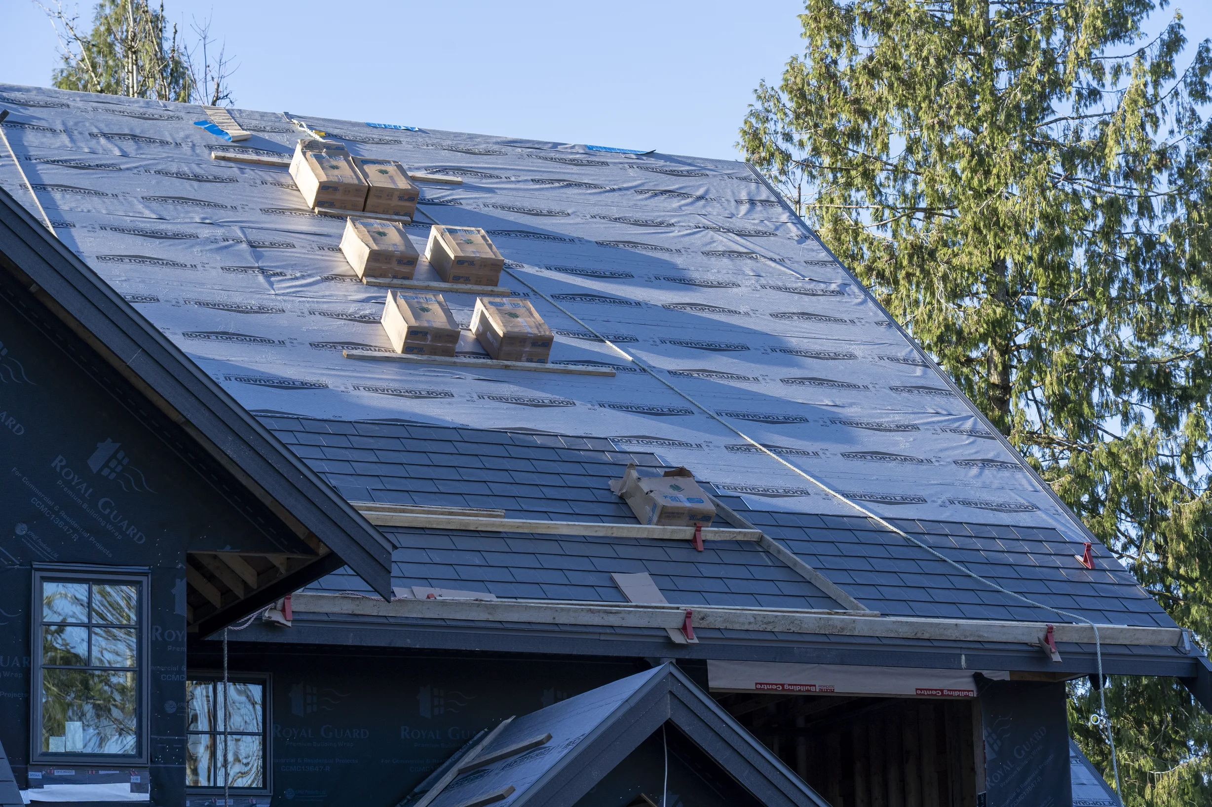 Musket Grey Interlock Slate aluminum roof being installed on a modern house with a metal roof under construction in a, Abbotsford, British Columbia
