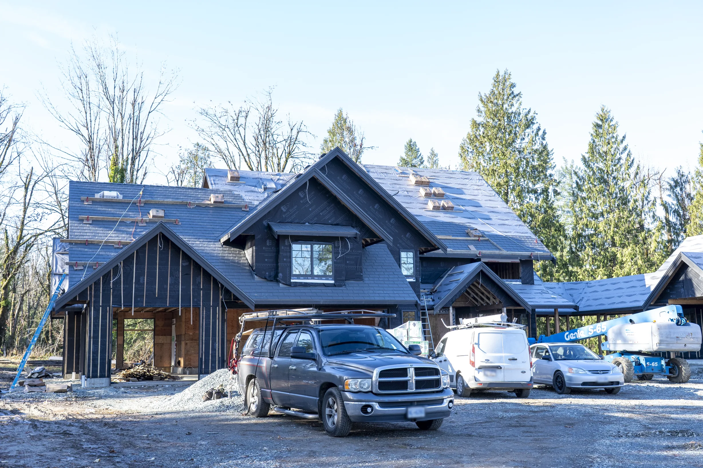 Musket Grey Interlock Slate aluminum roof being installed on a metal roof under construction in a forested area, Abbotsford, British Columbia