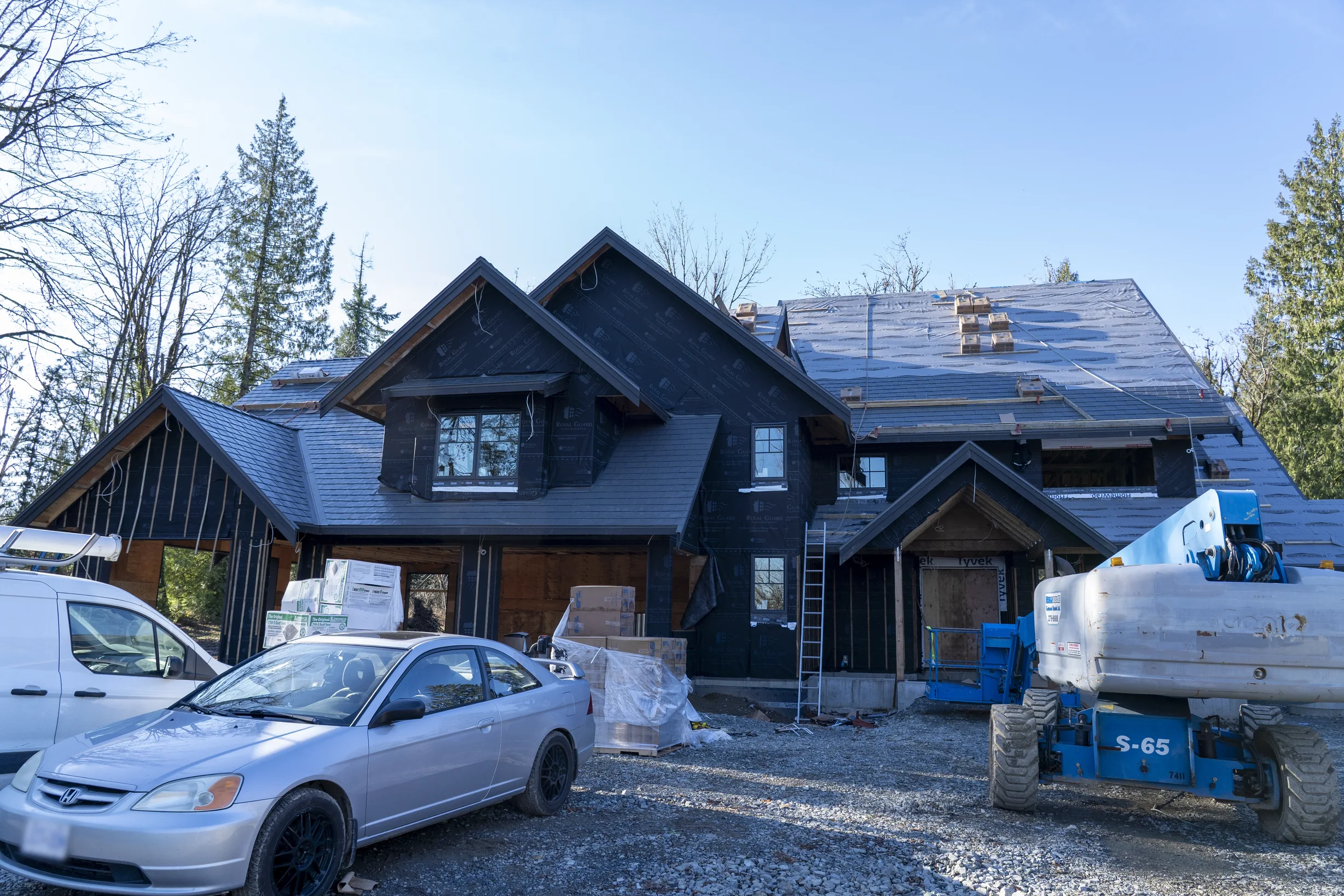 Musket Grey Interlock Slate aluminum roof being installed on a two-storey home under construction in the woods, Abbotsford, British Columbia
